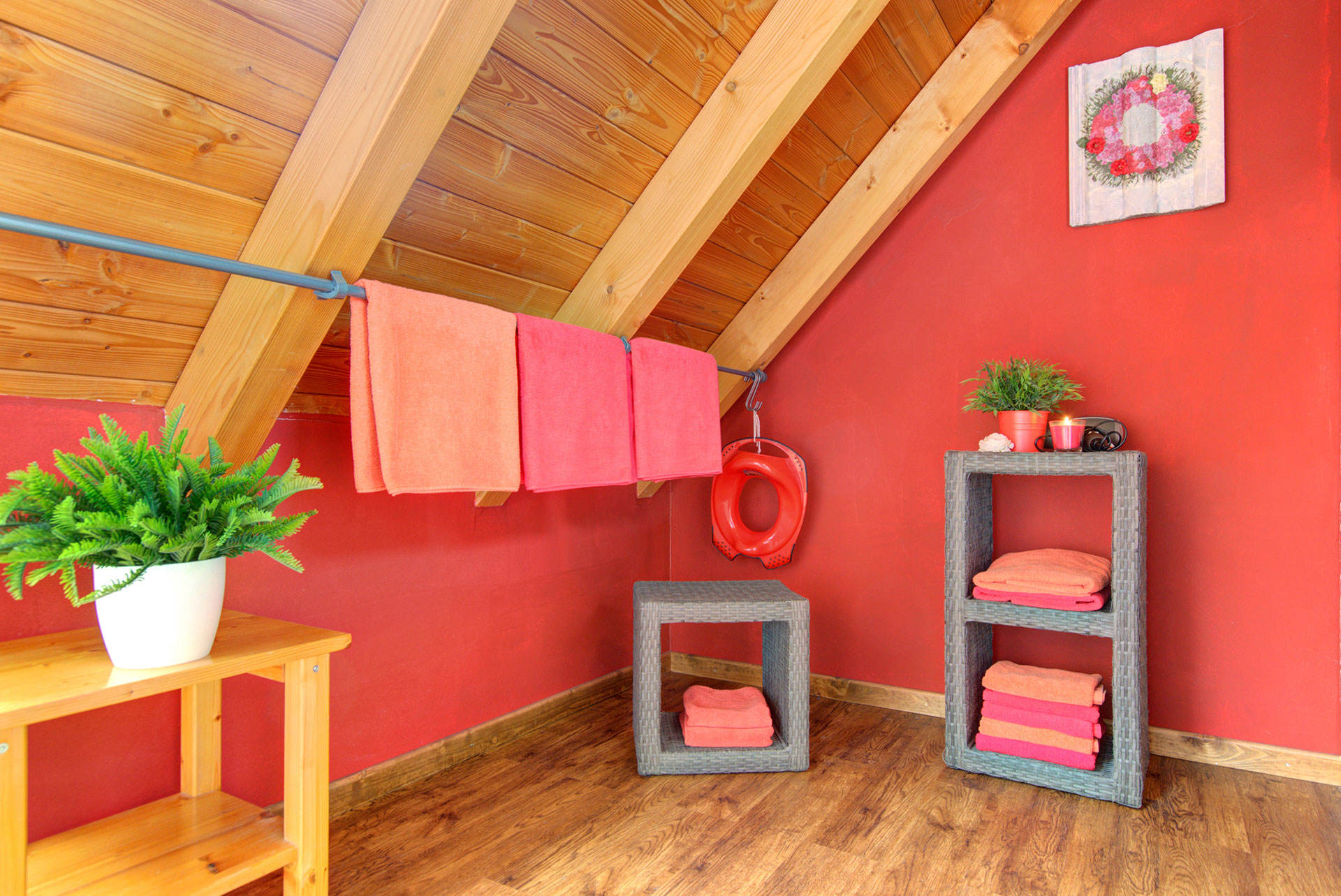 badezimmer in dachschräge und roten wänden mit kleinen möbeln und stange für handtücher im ferienhaus