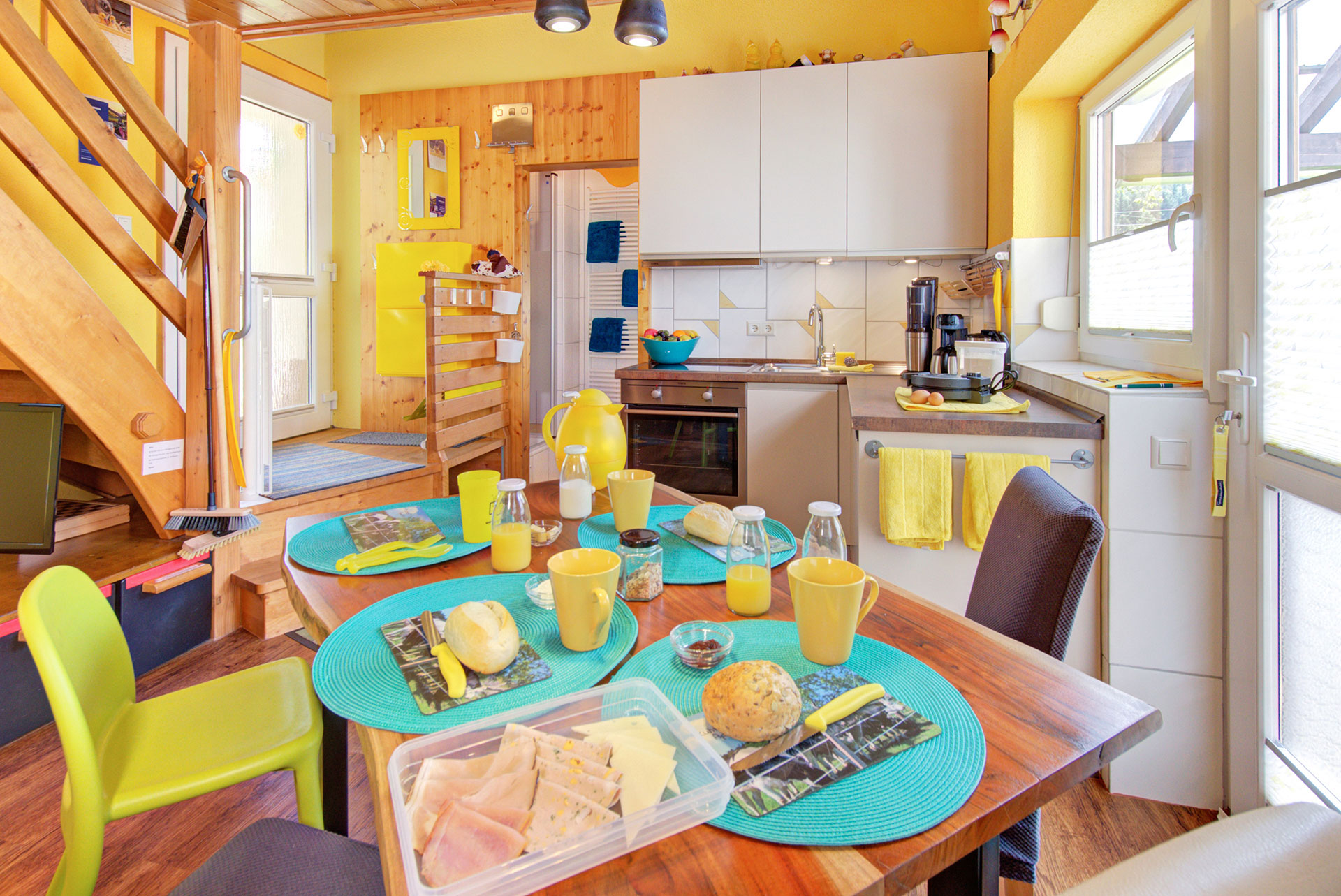 in tütkis und gelb gedeckter frühstückstisch mit blick zur küchenzeile in der Ferienwohnung