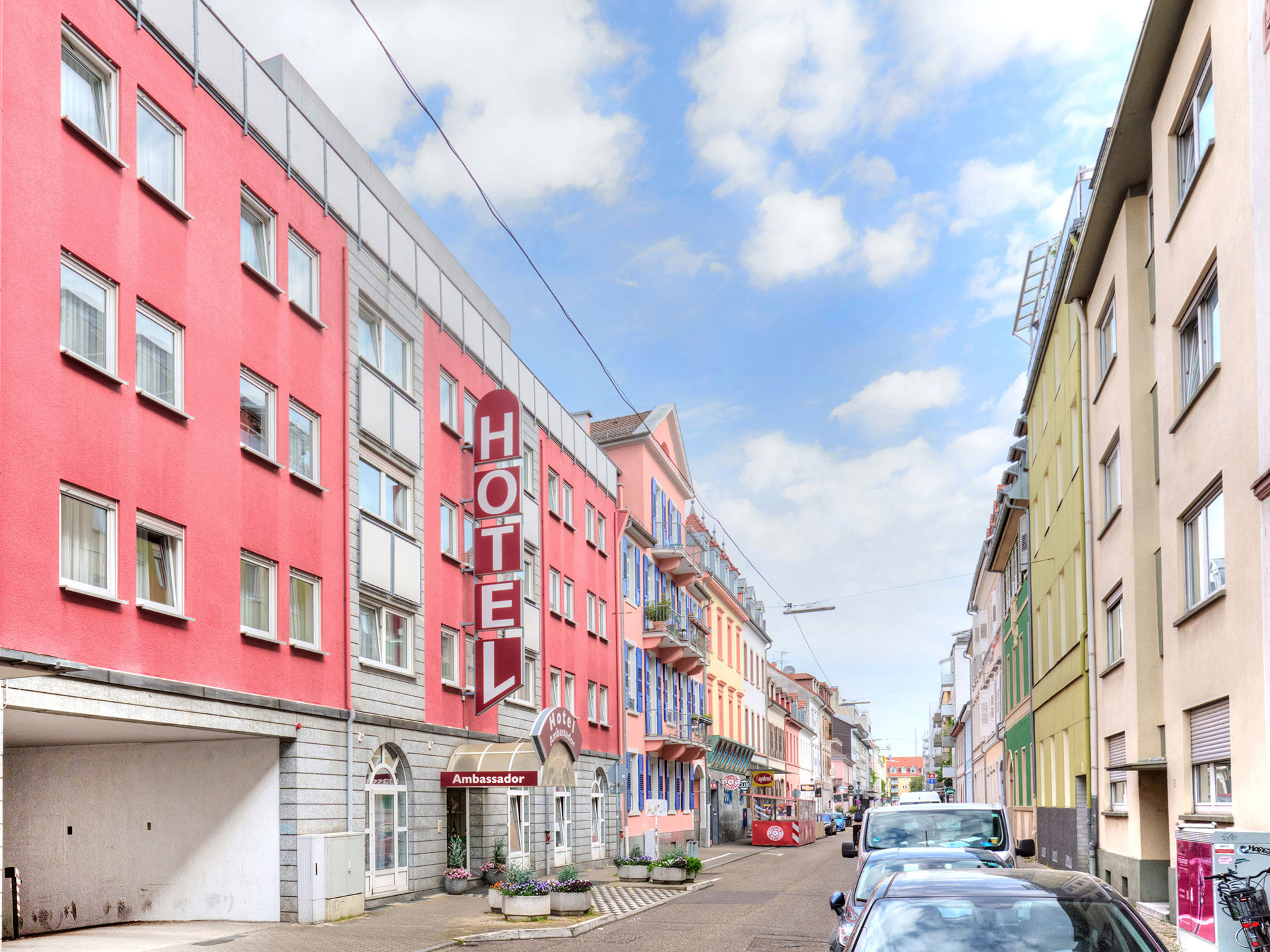 hotel vollständig am tag von außen seitlich mit blick in die Strasse und blauer himmel