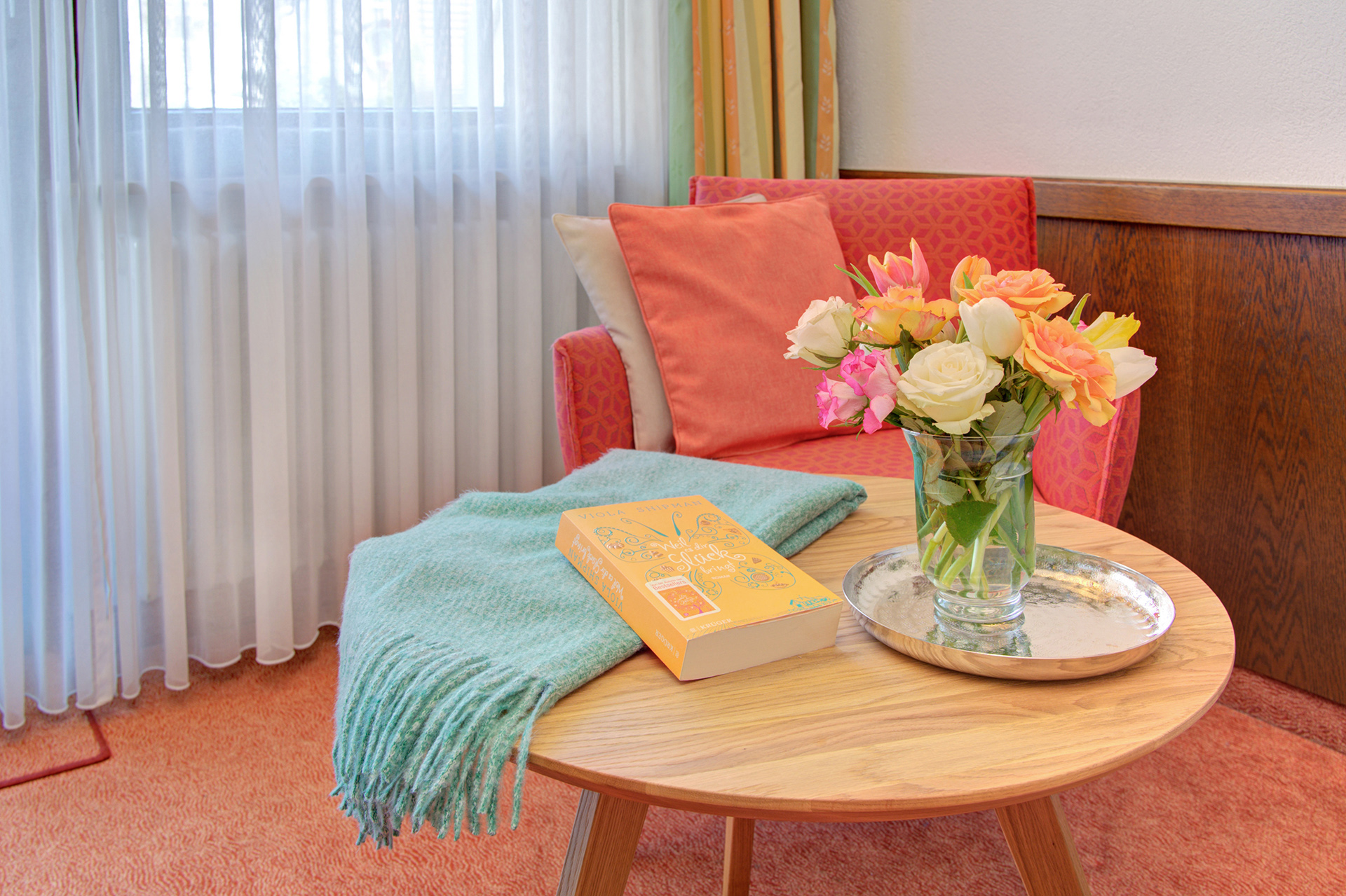 hotelfoto kleiner Tisch mit tulpen decke und orangenes buch