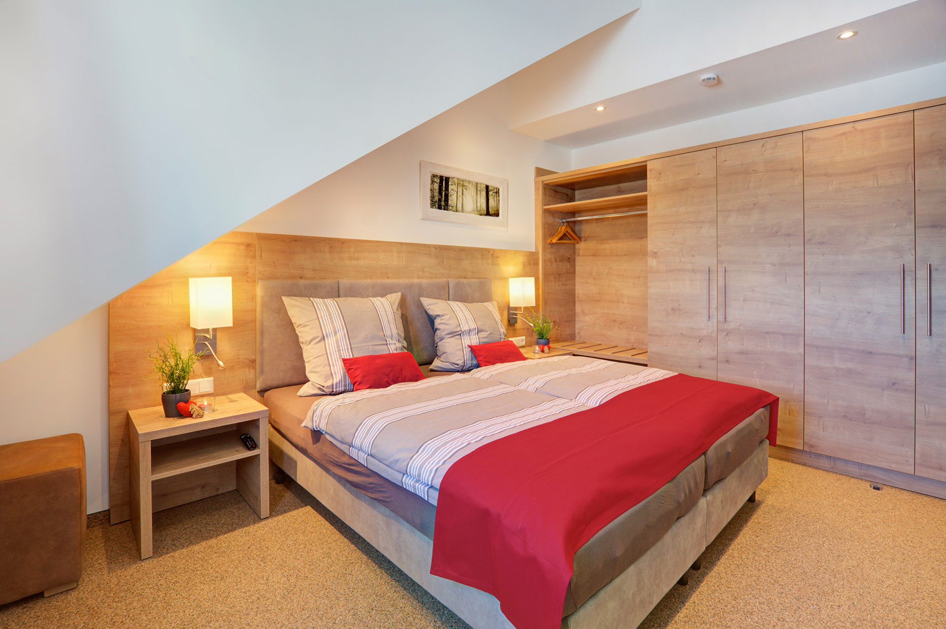doppelzimmer mit roten bettläufern und kissen in ferienwohnung