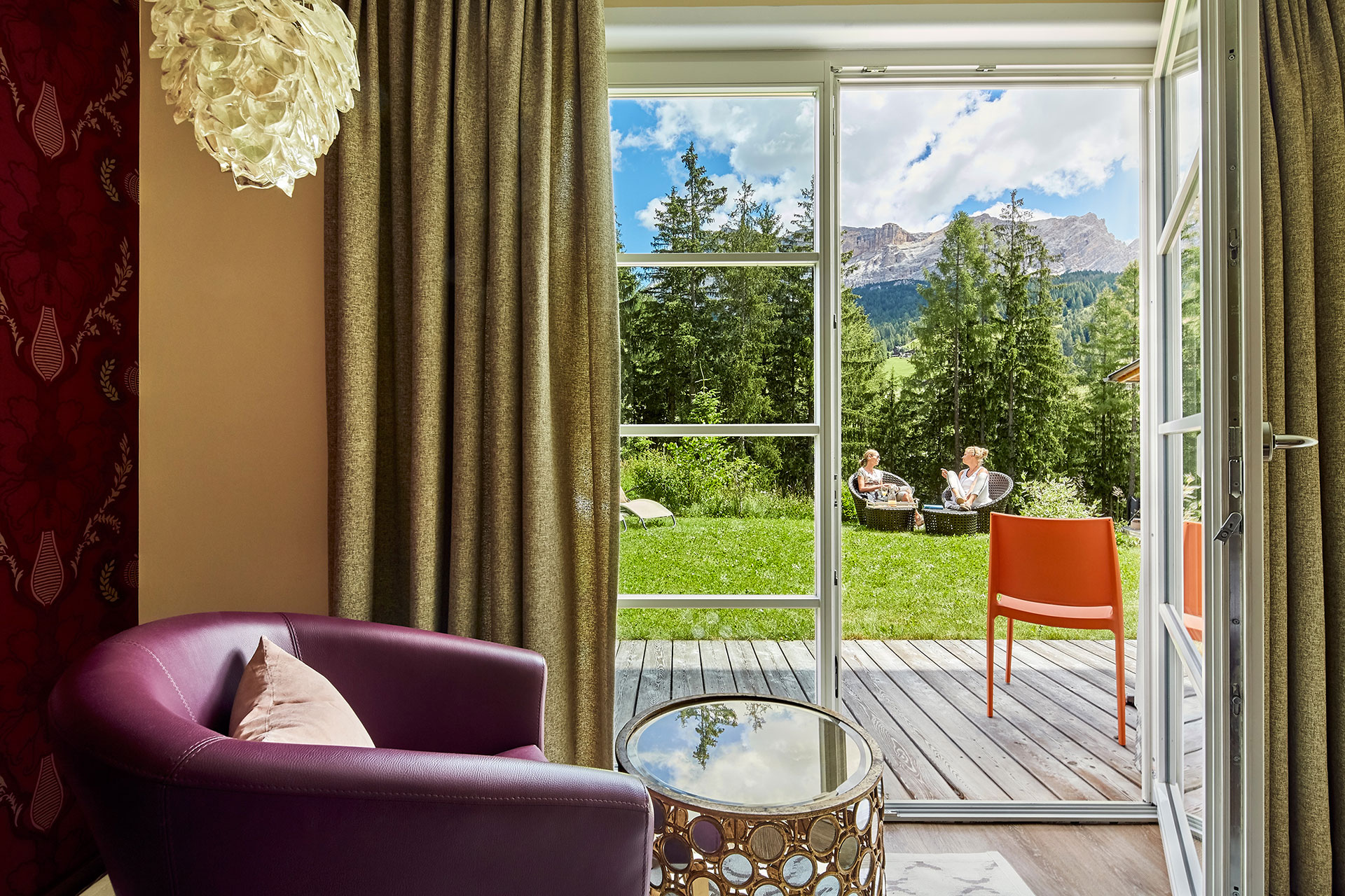 Blick durch Terrassentür auf einen grünen Garten, zwei Personen sitzen entspannt im Garten - vorher