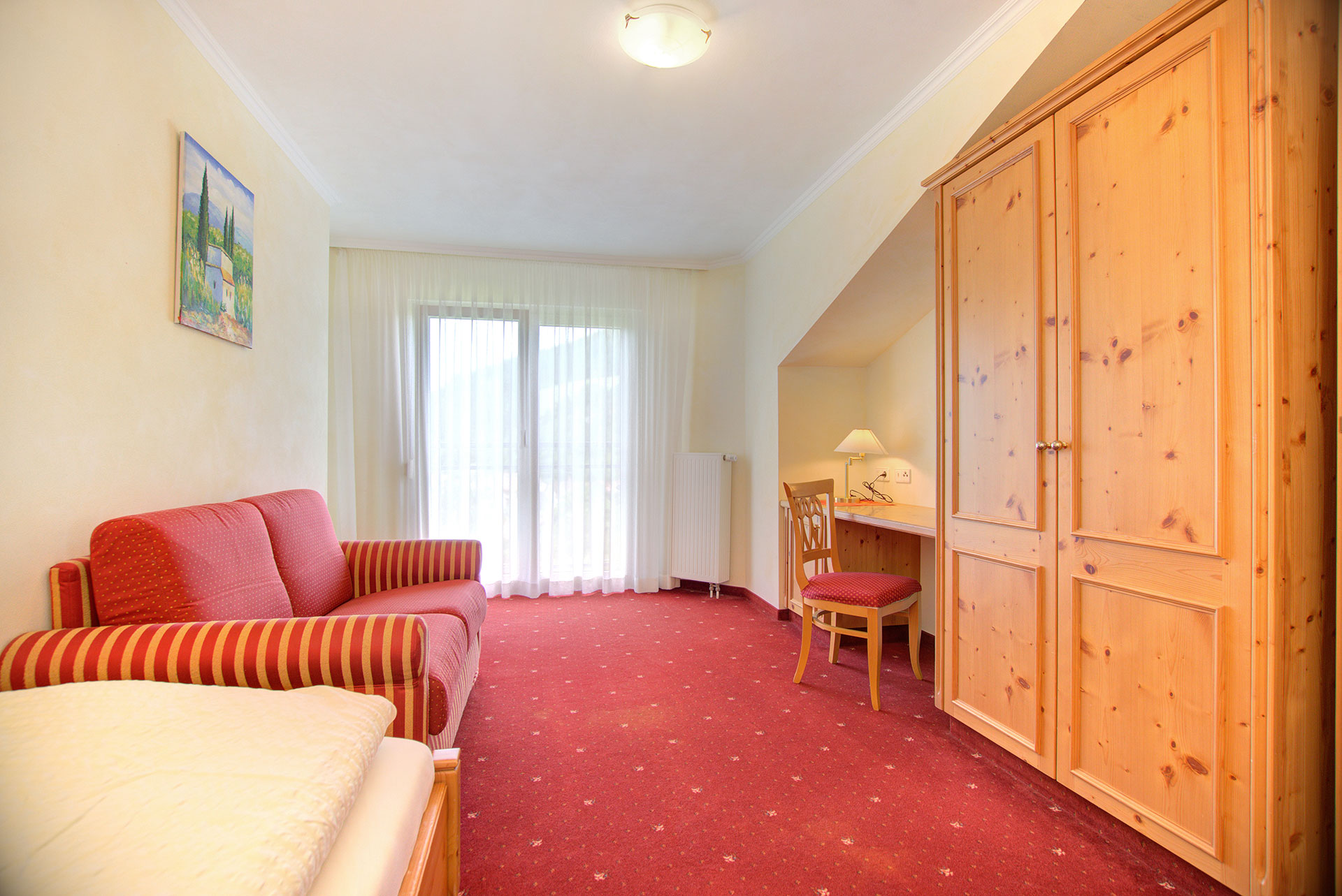 foto ferienwohnung einzelzimmer mit rotem sofa und arbeitsbereich sowie gardine geschlossen