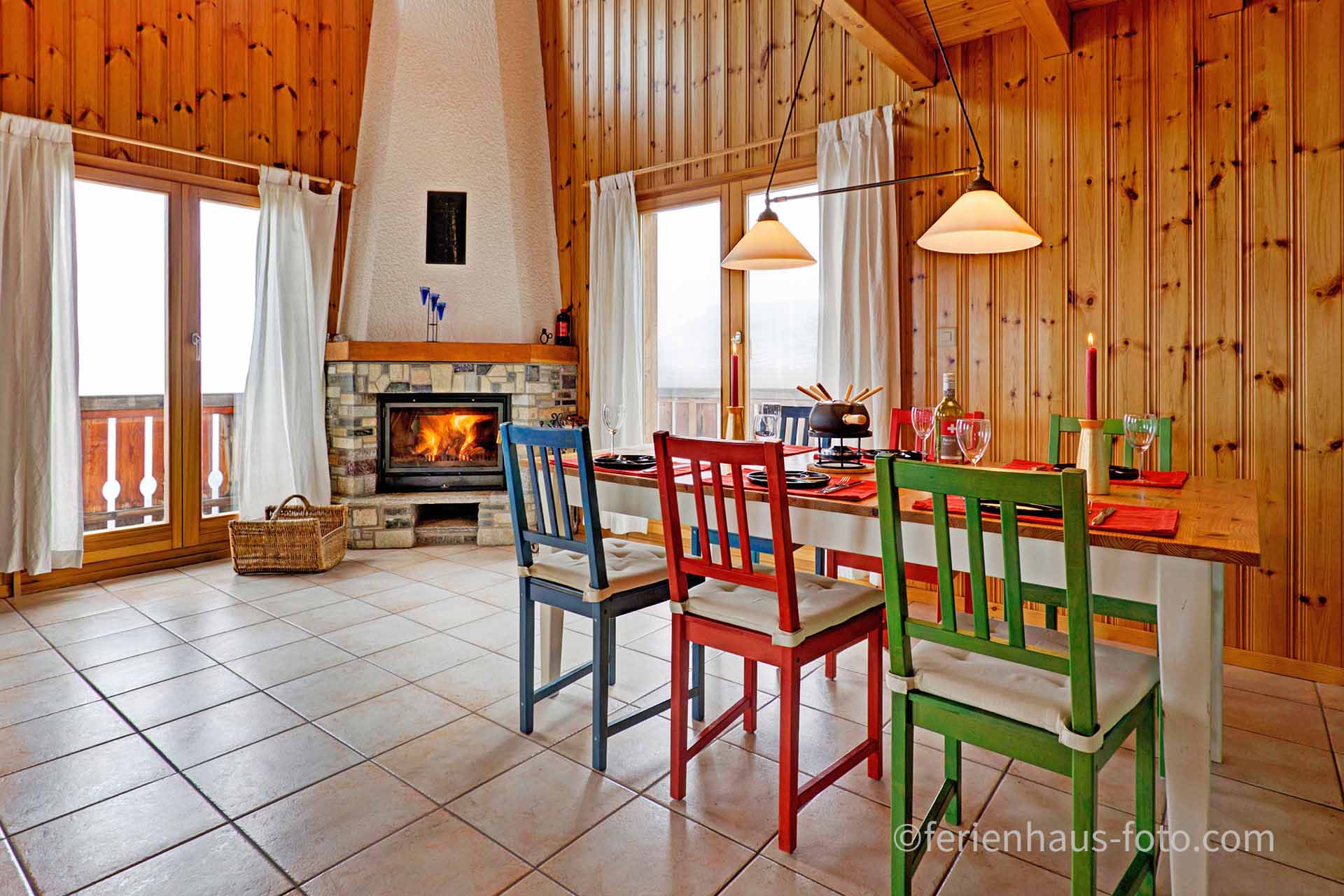 ferienhaus foto esszimmer mit rot grünen stühlen und offenem brenndendem kamin