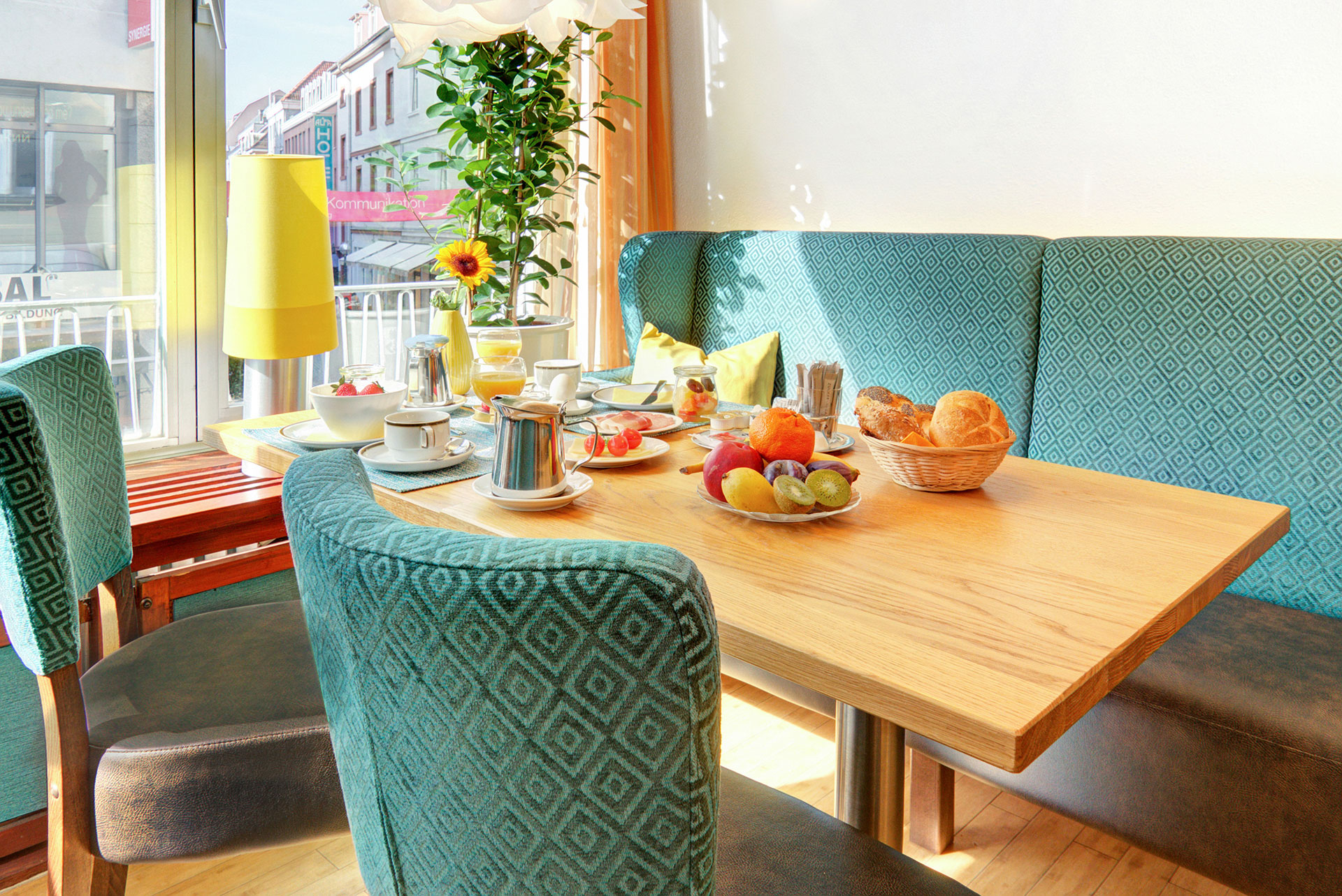 hotelfotograf tuerkisene sitzecke mit fruehstueckstisch mit muesli fruechten broetchen und blick auf die stadt