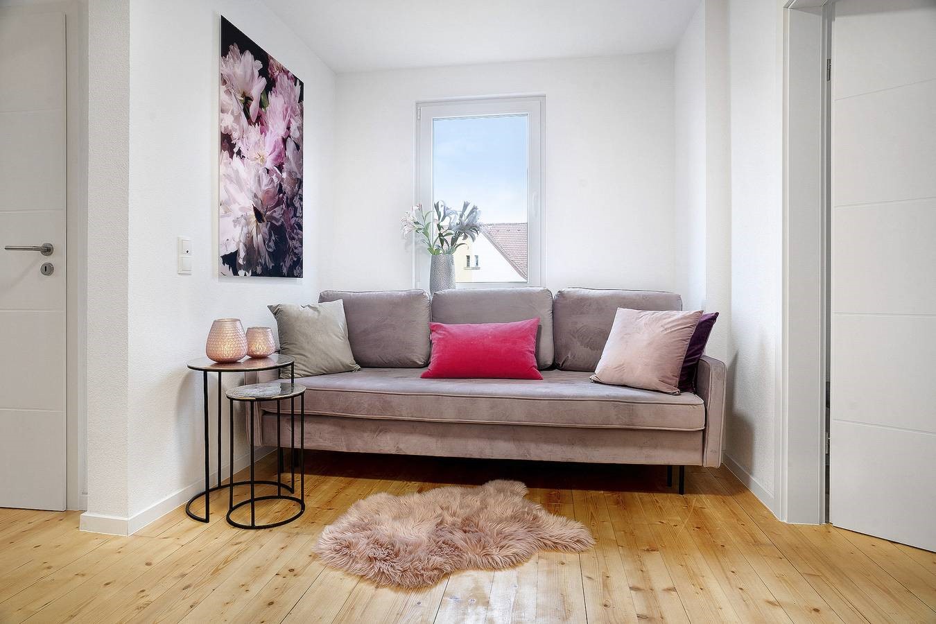 graues Sofa mit blütenbild und kleinem tisch mit rosa teelichtern