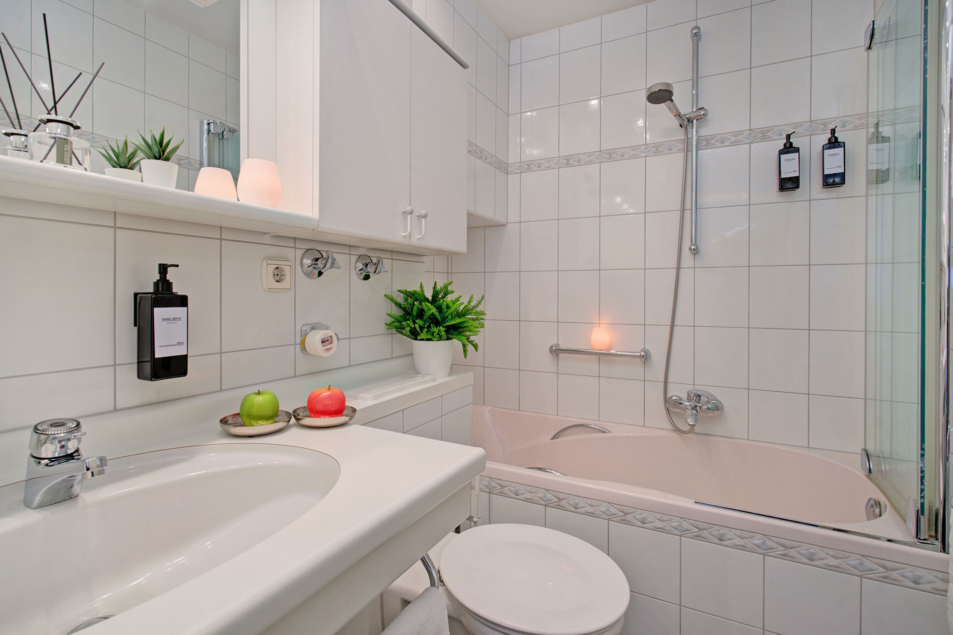 einladendes kleines badezimmer mit waschbecken und badewanne sowie teelicht