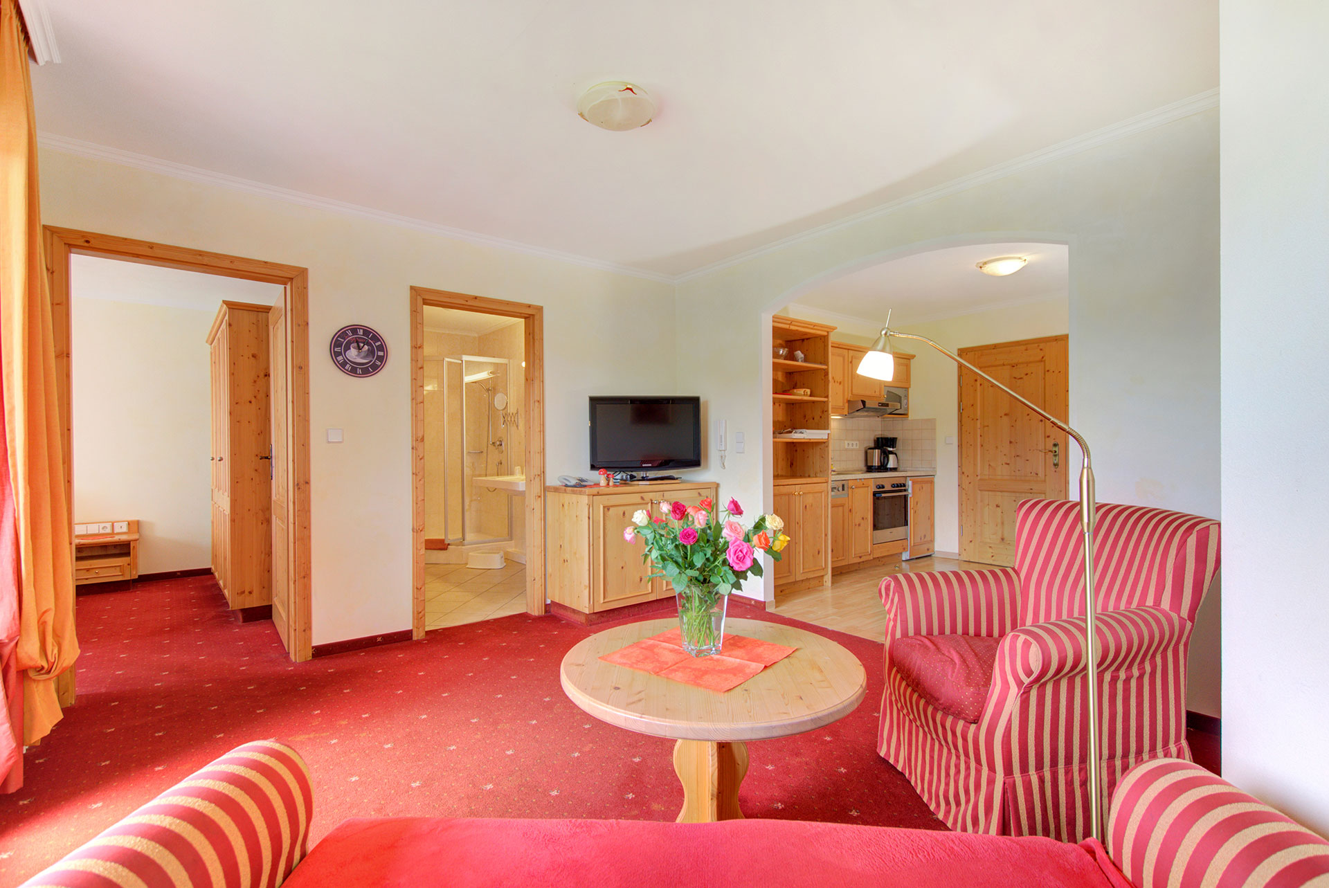 foto ferienwohnung blick von roter sitzgruppe zur kueche und tueren doppelzimmer sowie badezimmer