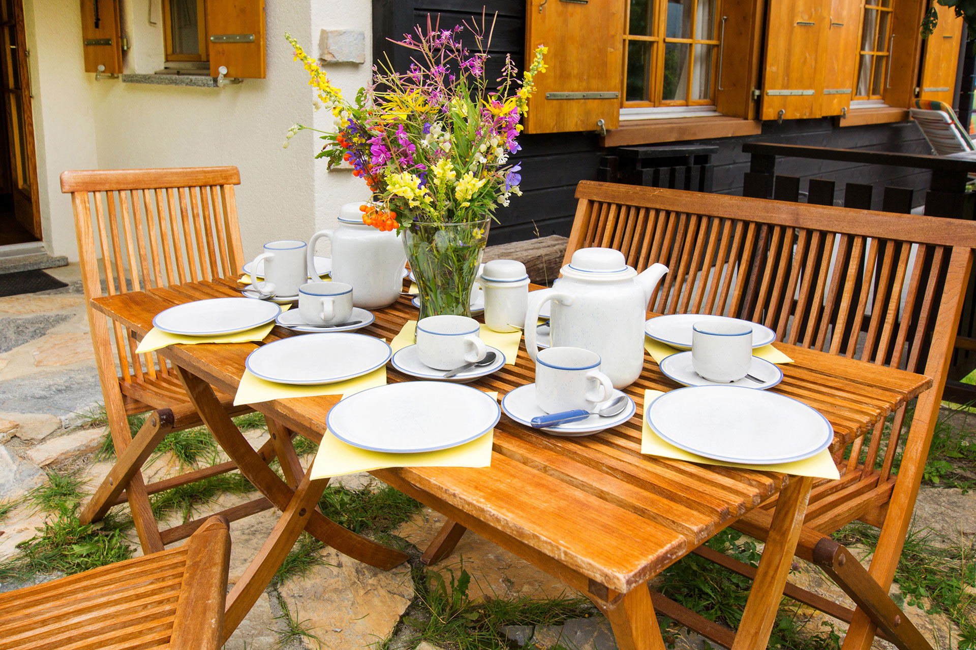 ferienhaus foto fruehlingshaft gedeckter tisch mit wiesenblumenstrauss auf terrasse 