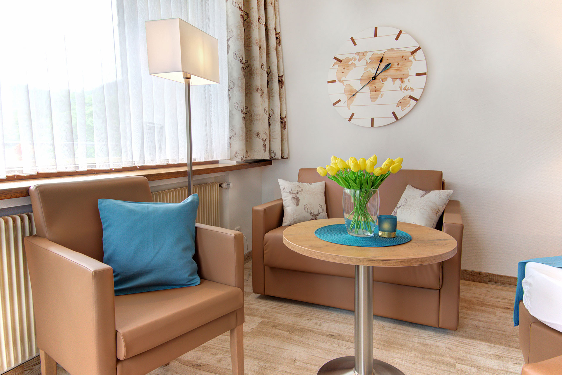sitzgruppe in braun türkis und gelbem tulpenstrauss auf tisch in apartment