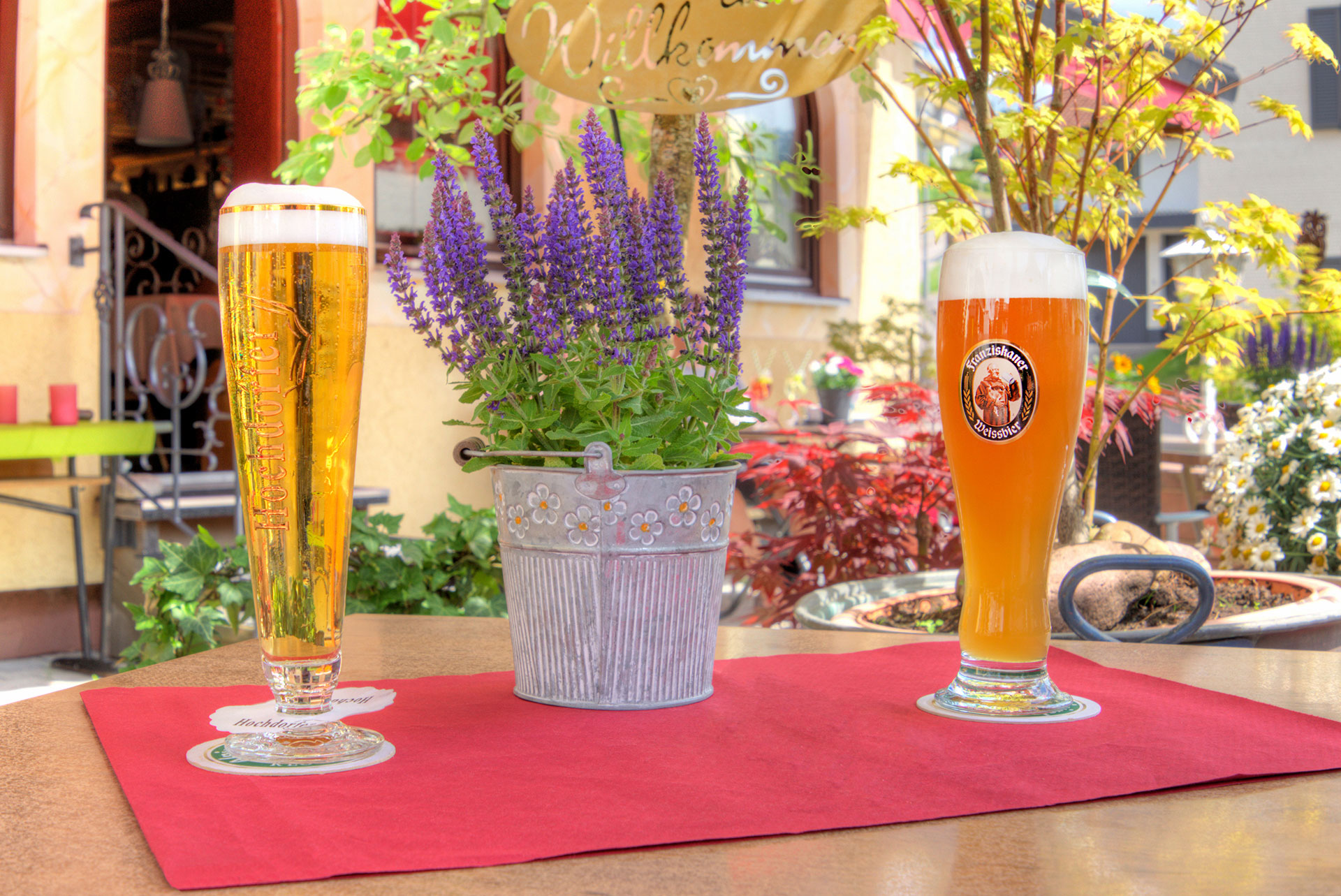 hotelfoto biergarten mit detailblick auf tisch mit zwei frisch gezapten bieren sowie lavendeltoepfchen