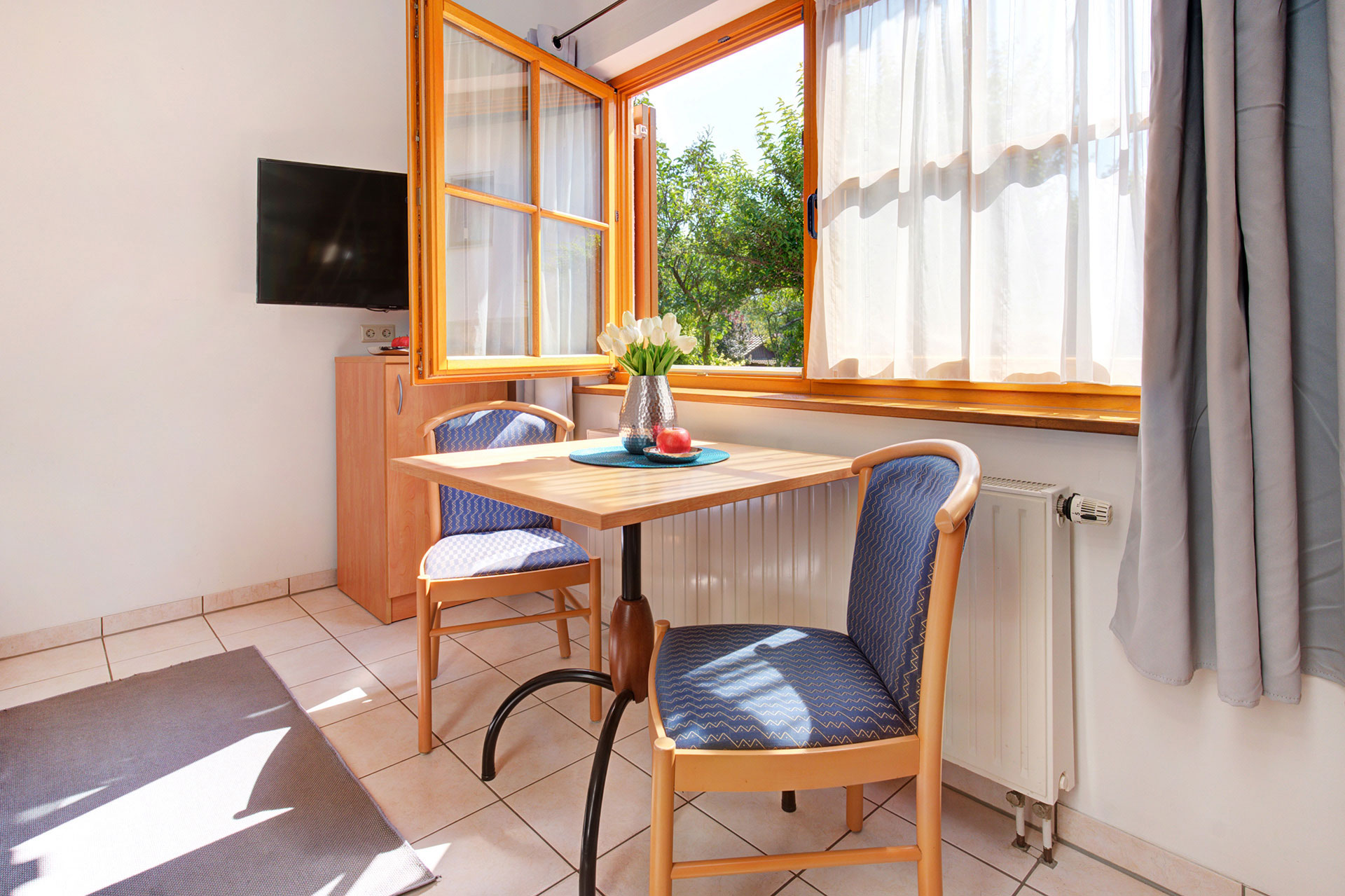 ferienwohnung fotografieren - geöffnetes Sommerfenster mit Tisch und Stühlen für zwei Personen