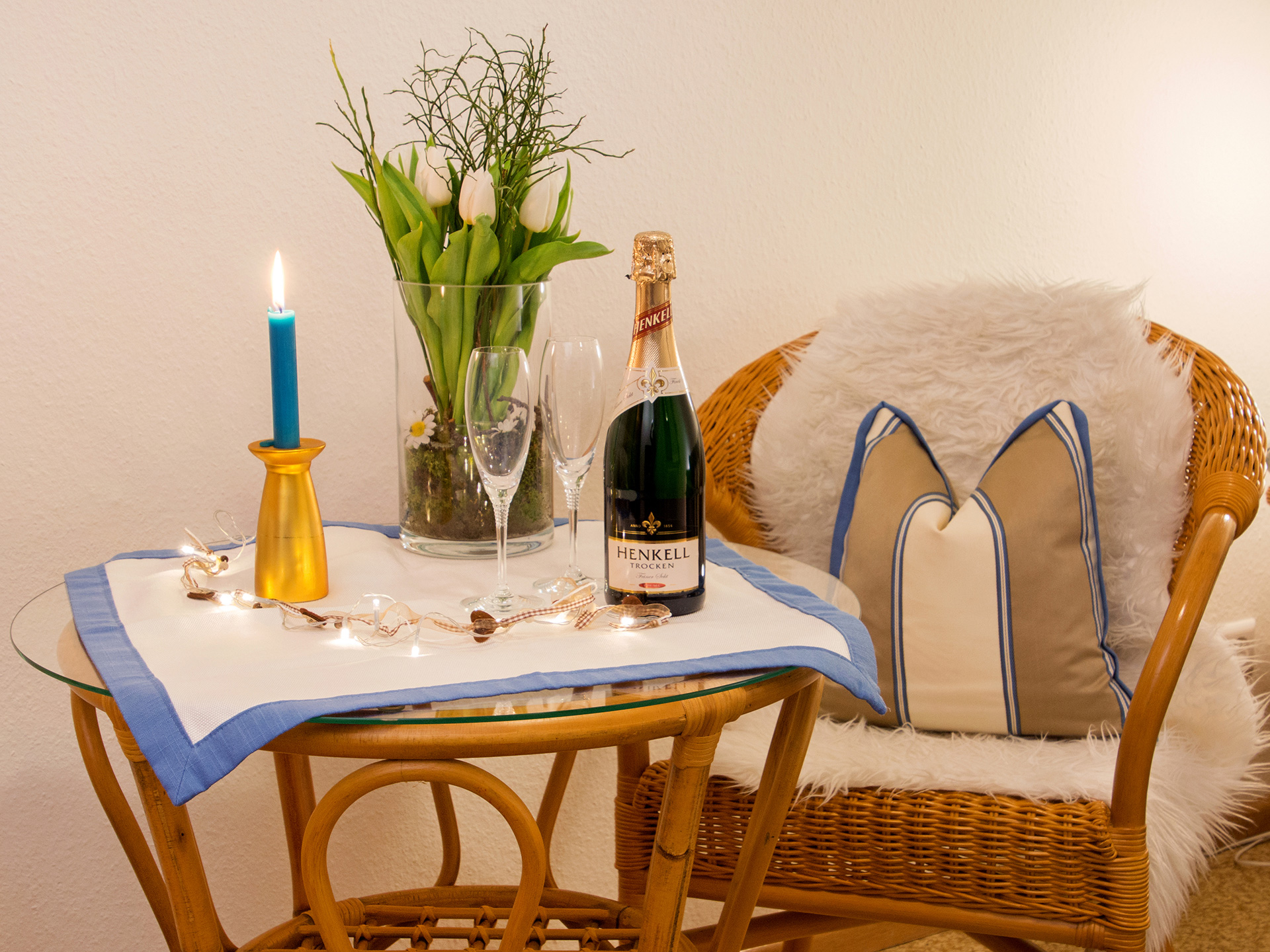 ferienwohnung fotografieren sitzgruppe aus korbgeflecht mit Sektflasche kerze und tulpenstrauss