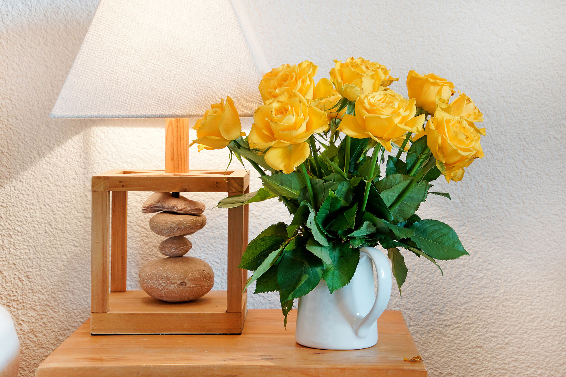 ferienhaus foto nachttisch mit lampenschirm und gelbem rosenstrauch