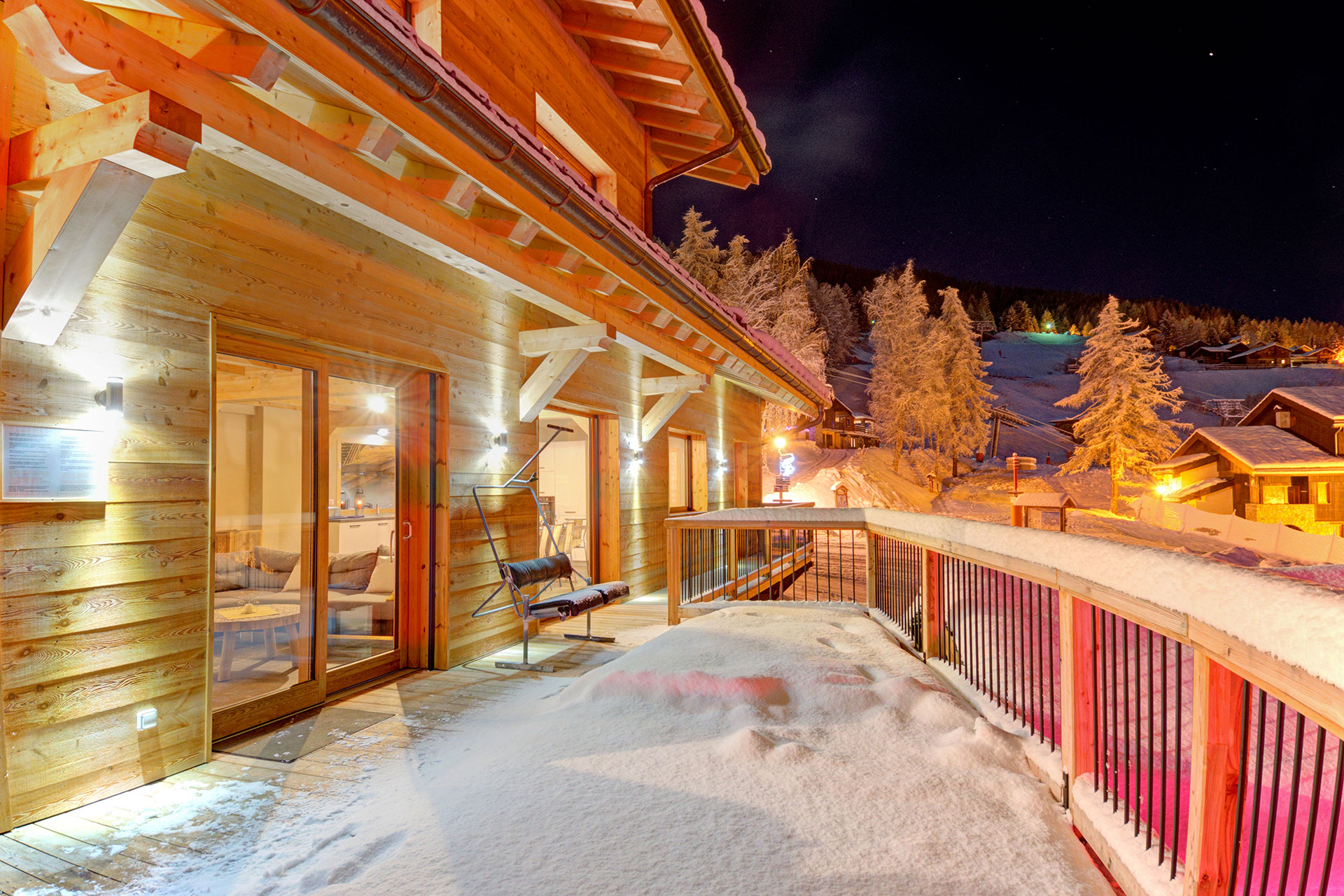 ferienhaus foto schneebedeckter balkon nachts vor leuchtendem holzchalet