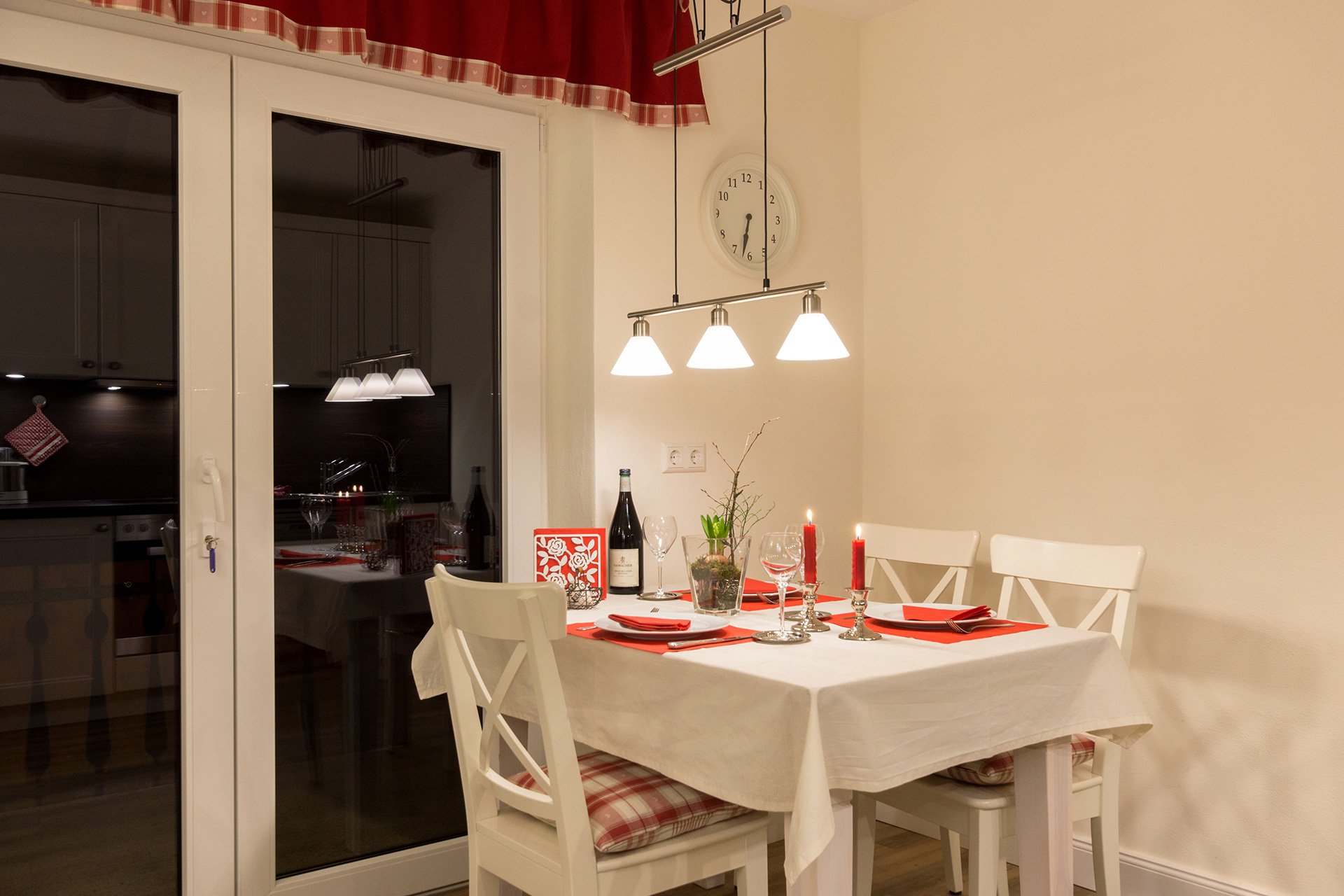ferienwohnung fotografieren rot eingedeckter tisch mit weiser tischdecke und nachtfenster