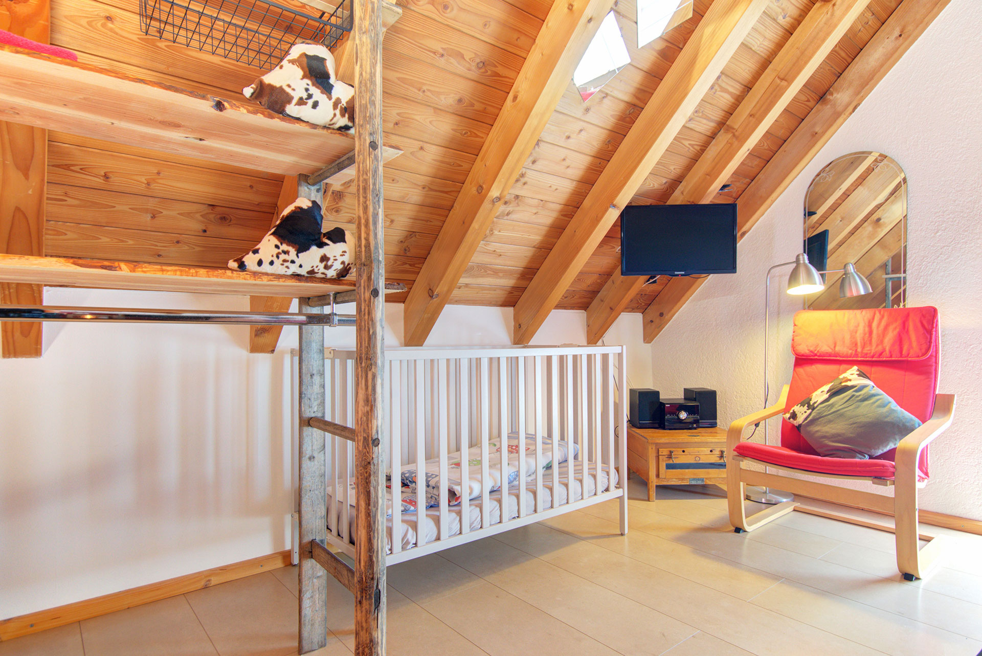 weises kinderbett mit schwingsessel und Tv-Monitor im ferienhaus