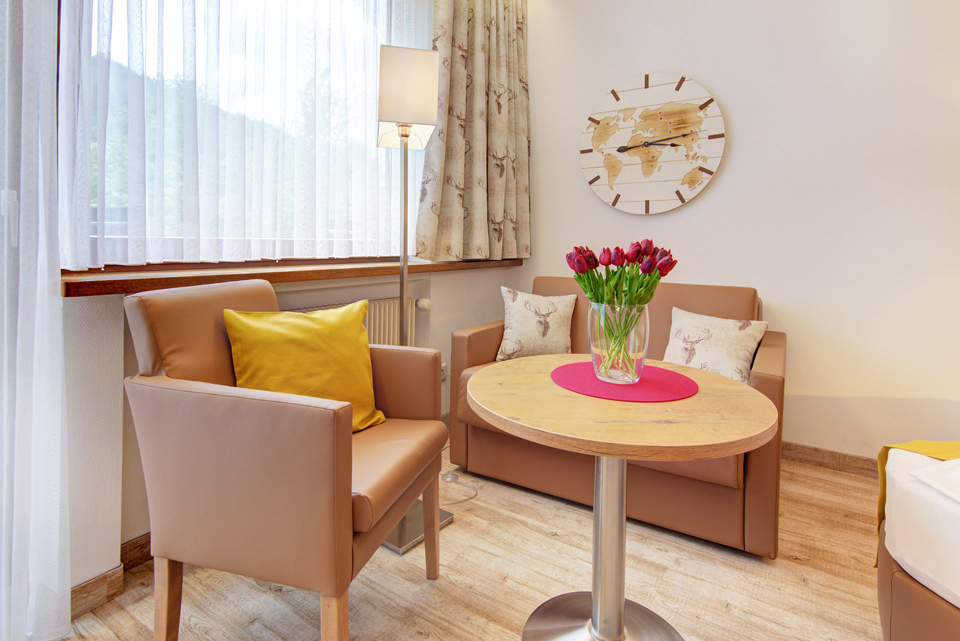 sitzgruppe in braun ocker mit rotem tulpenstrauss auf tisch in apartment