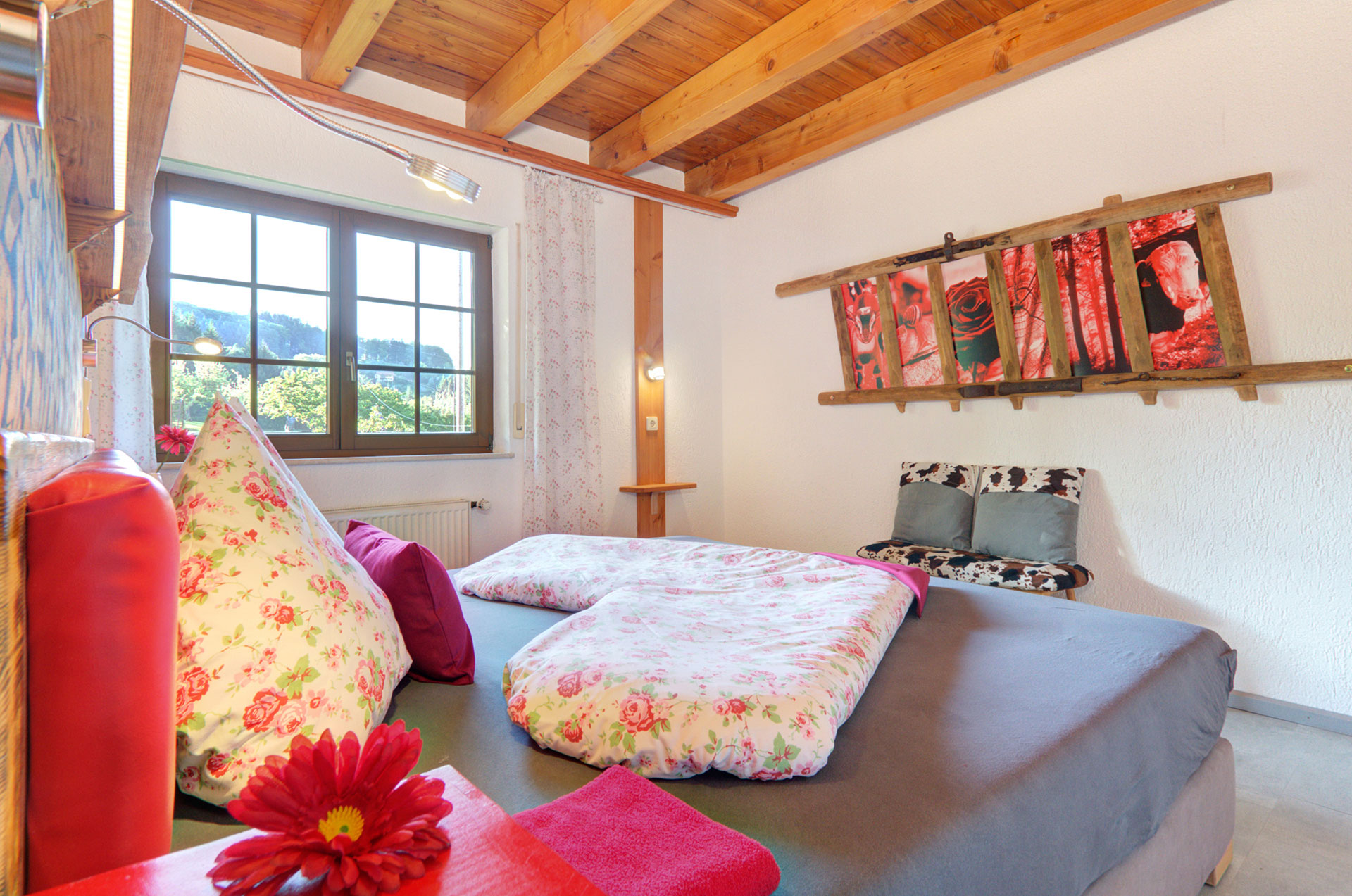 doppelzimmer mit blüte auf nachttisch und bettwäsche in herzform im ferienhaus