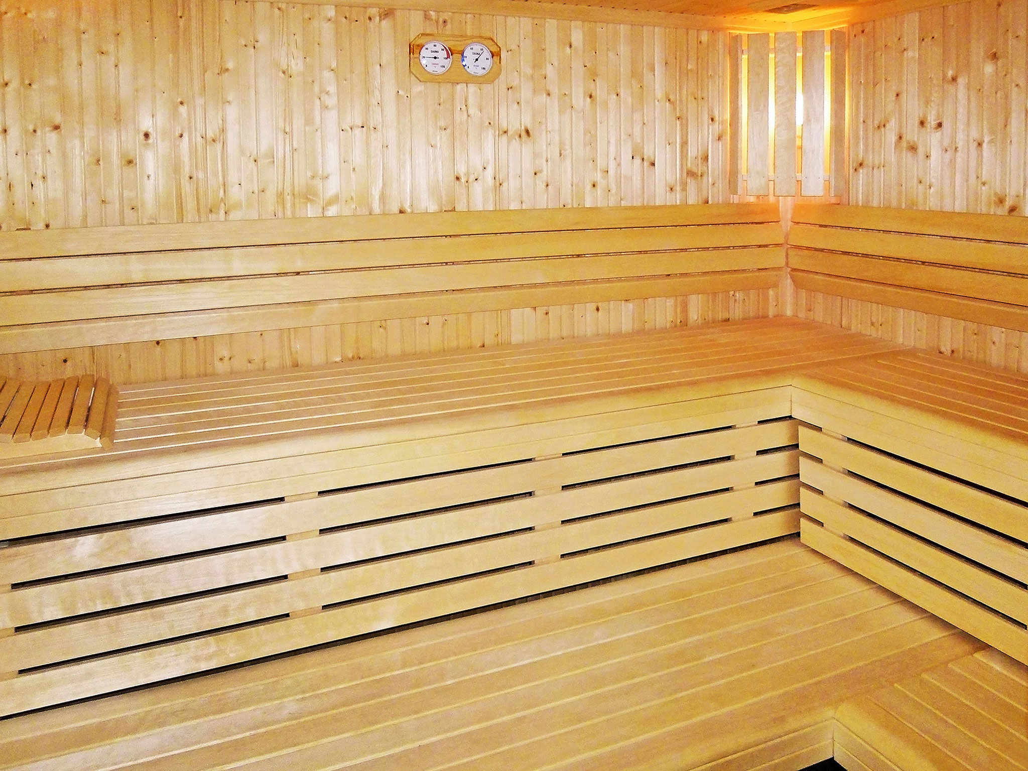 Helle Sauna in einem Ferienhaus, freundlich ausgeleuchtet, klare Linien und warme Holztöne
