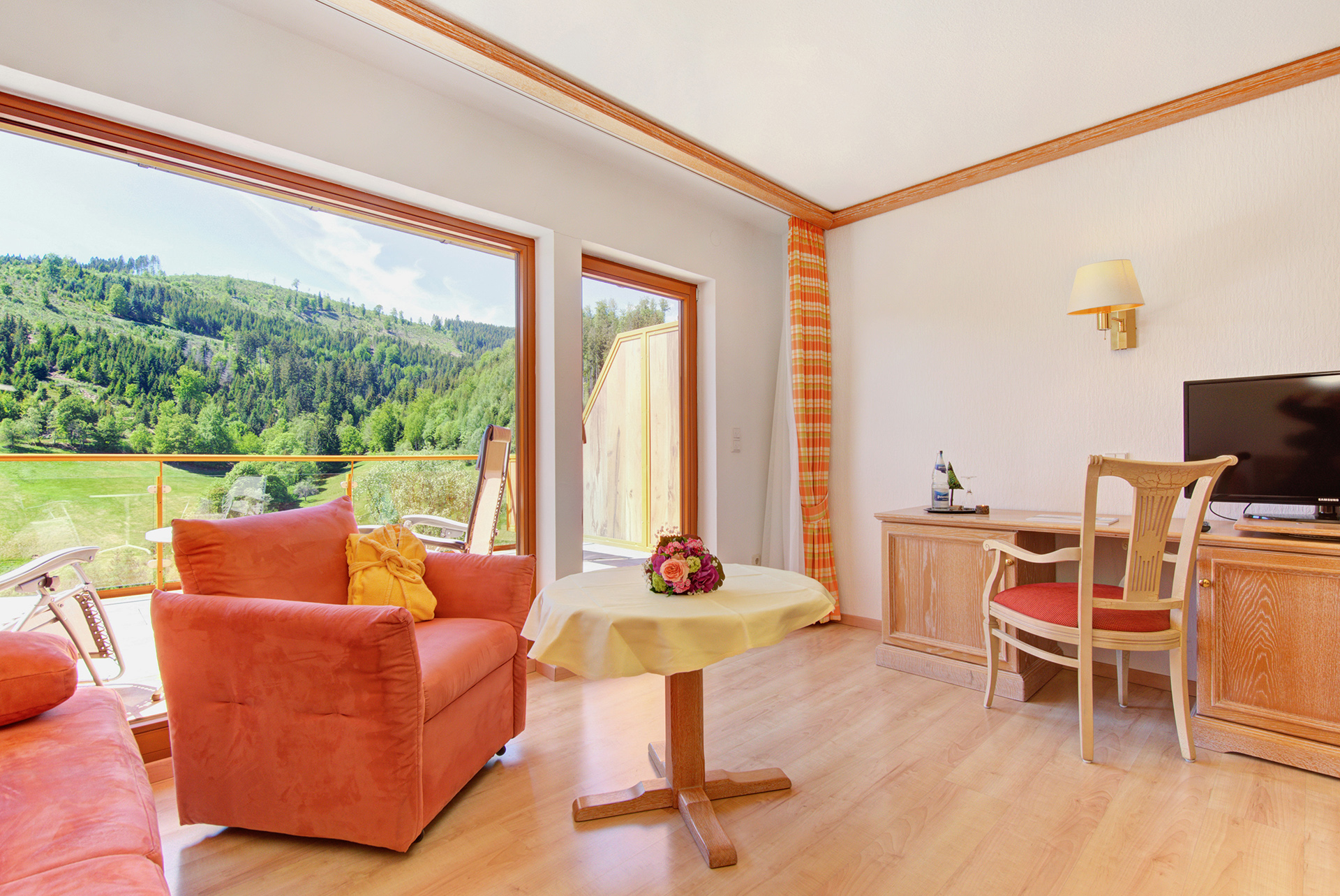 hotelfotograf roter sessel und kleiner tisch mit blumen und blick in den garten