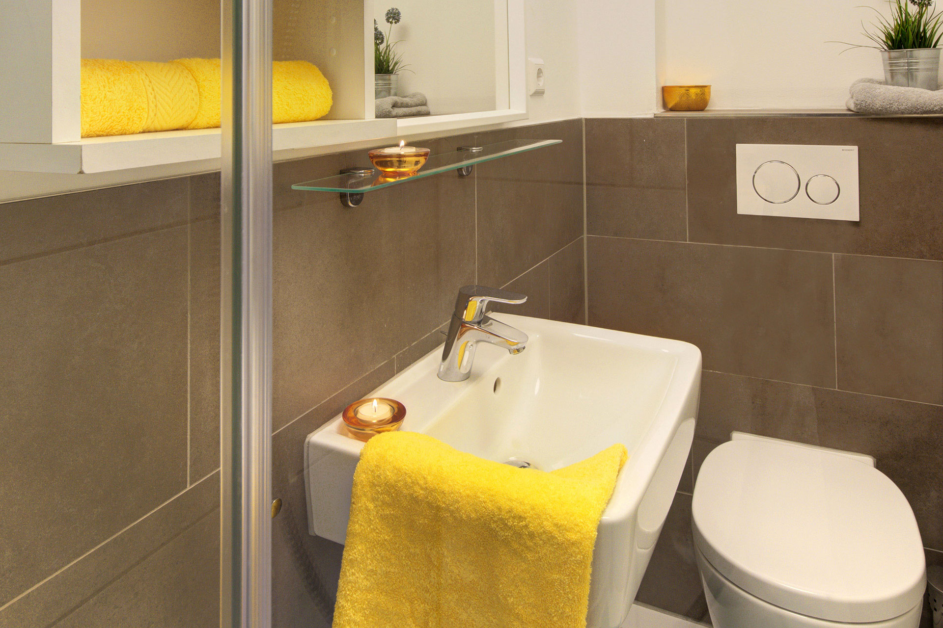 fotografin dekoriert kleines badezimmer mit gelbem handtuch und teelichtern