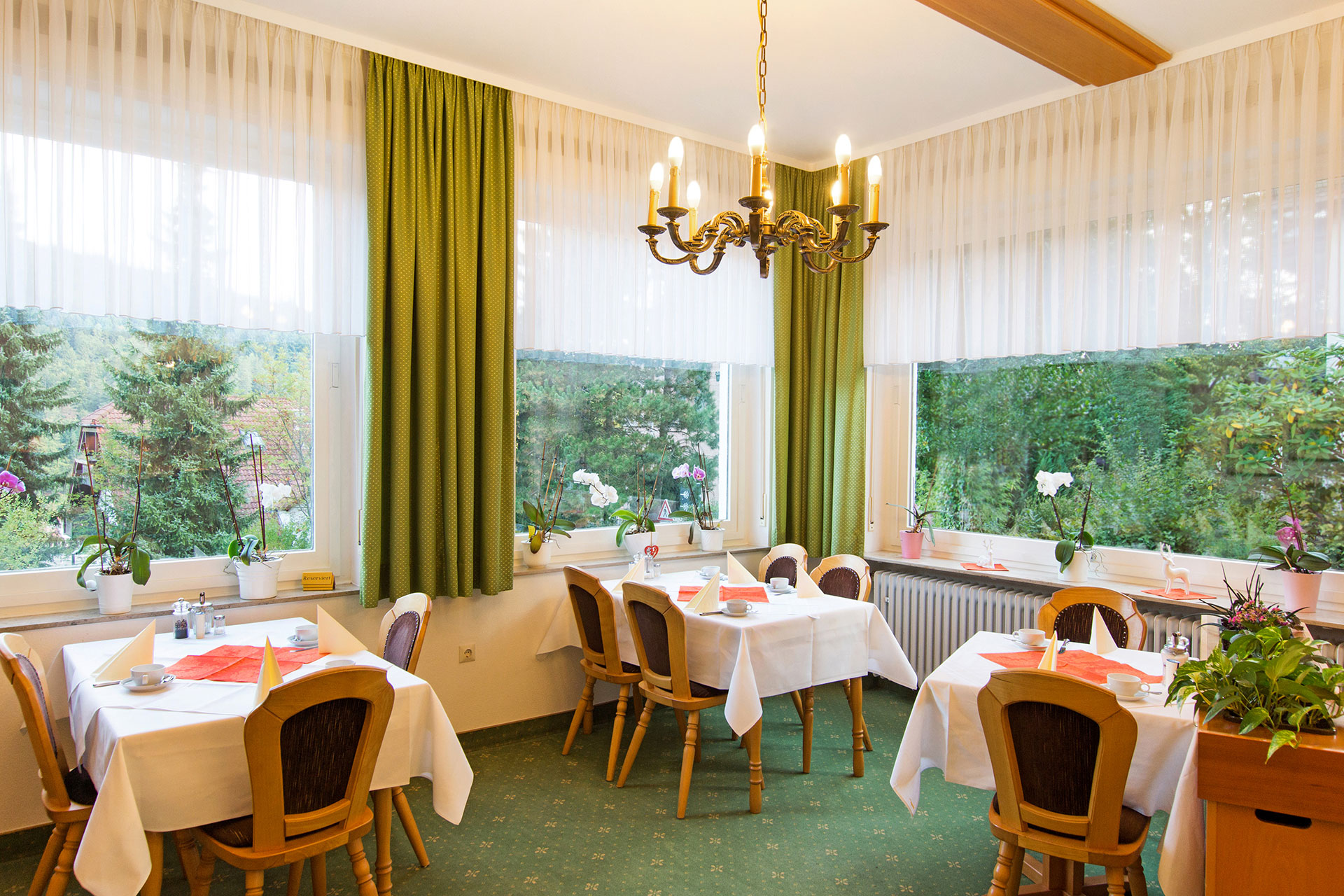 hotelfoto fruehstuecksraum mit drei gedeckten tischen und blick in den garten