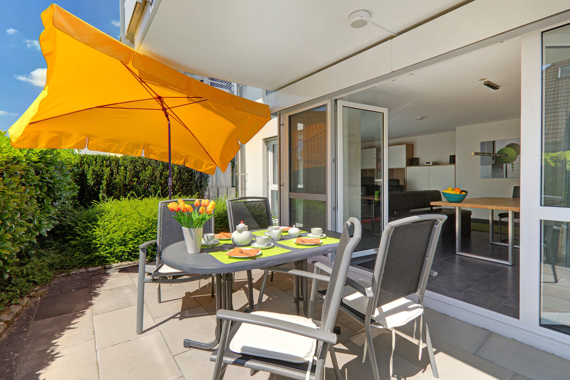 terrasse im Erdgeschoss mit gedecktem Tisch und gelbem Sonnenschirm in ferienwohnung