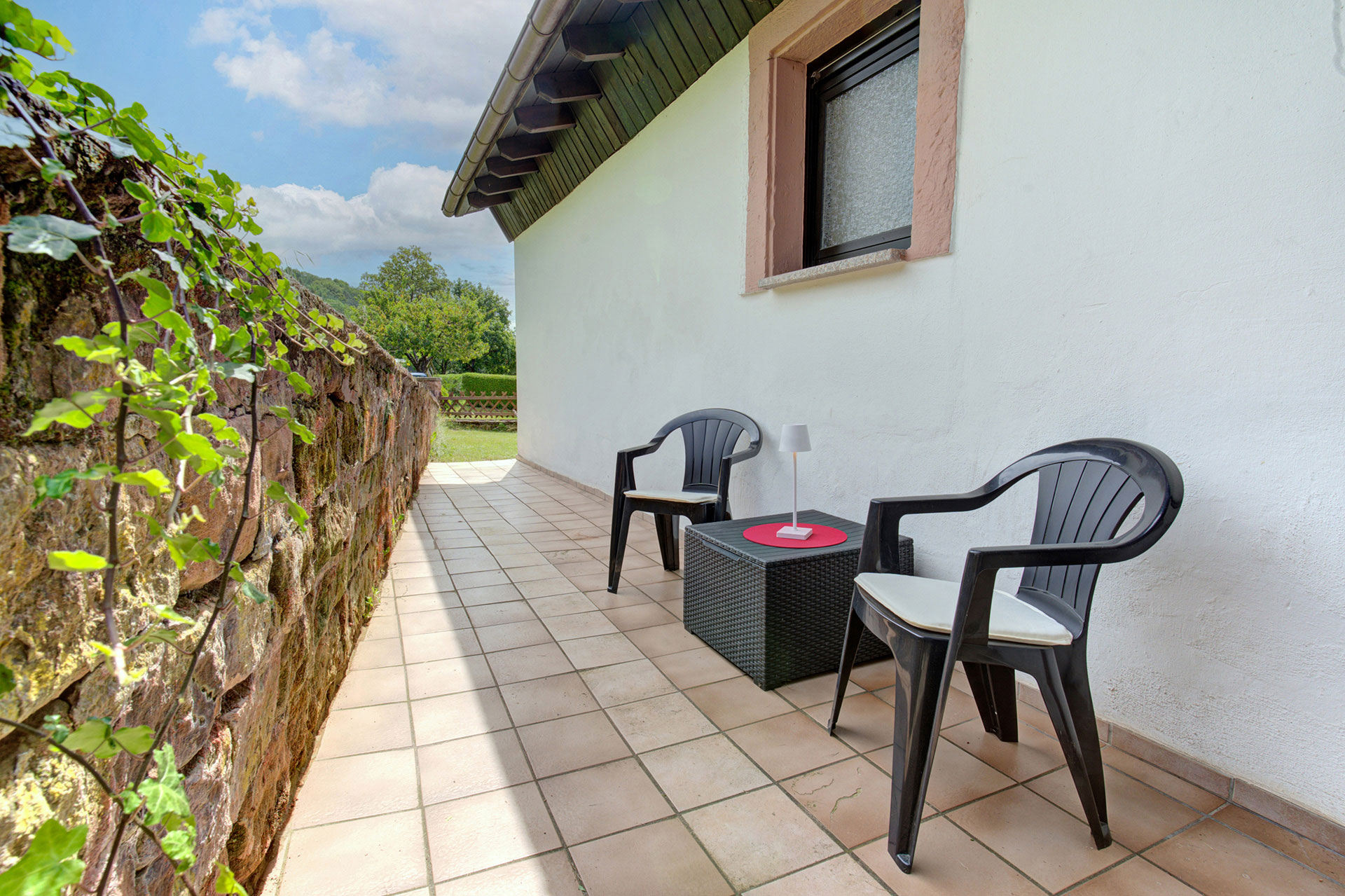 Ferienhaus von hinten mit zwei Stühlen und Tisch