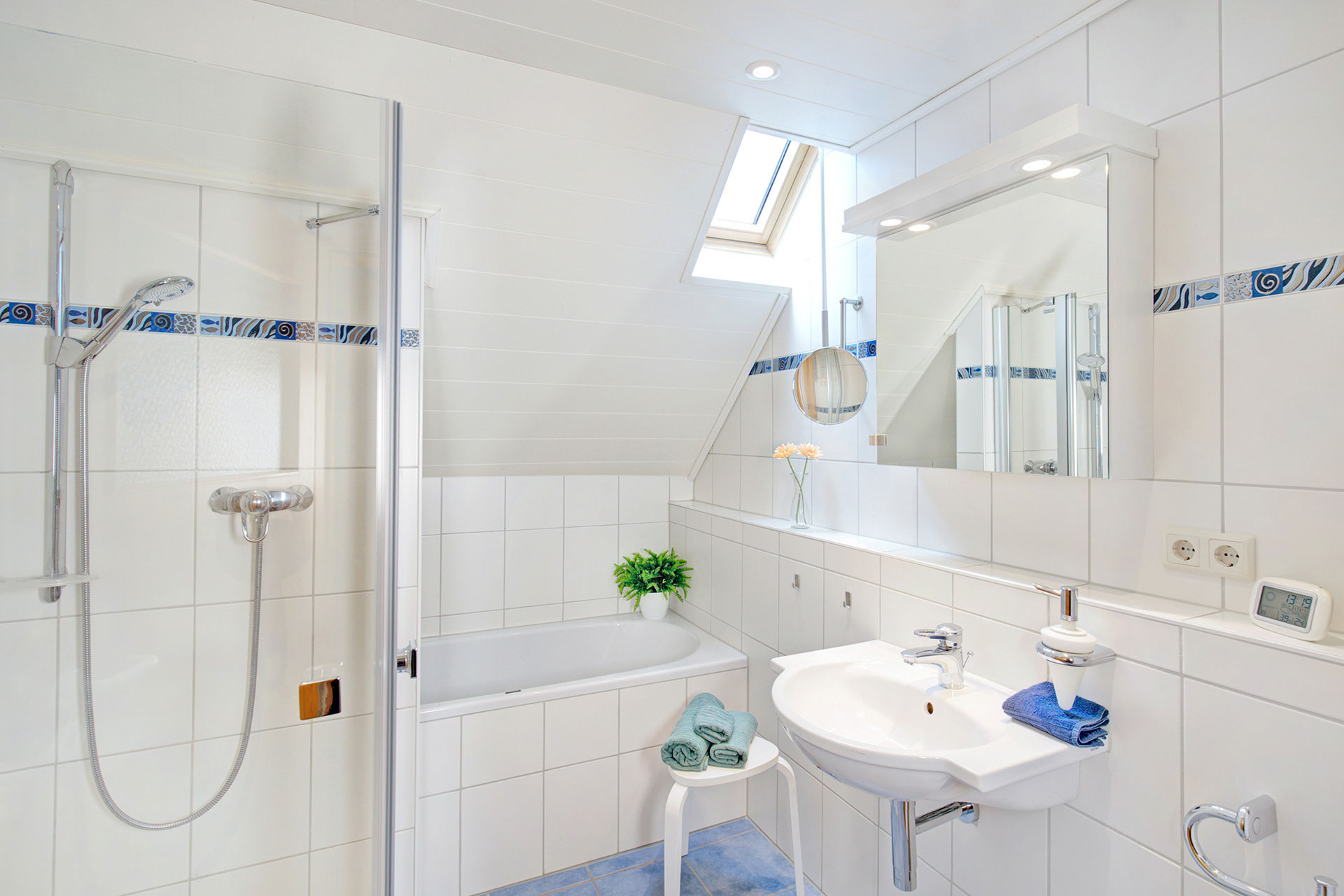 weises badezimmer mit gerbara in vase und grünpflanze in ferienhaus