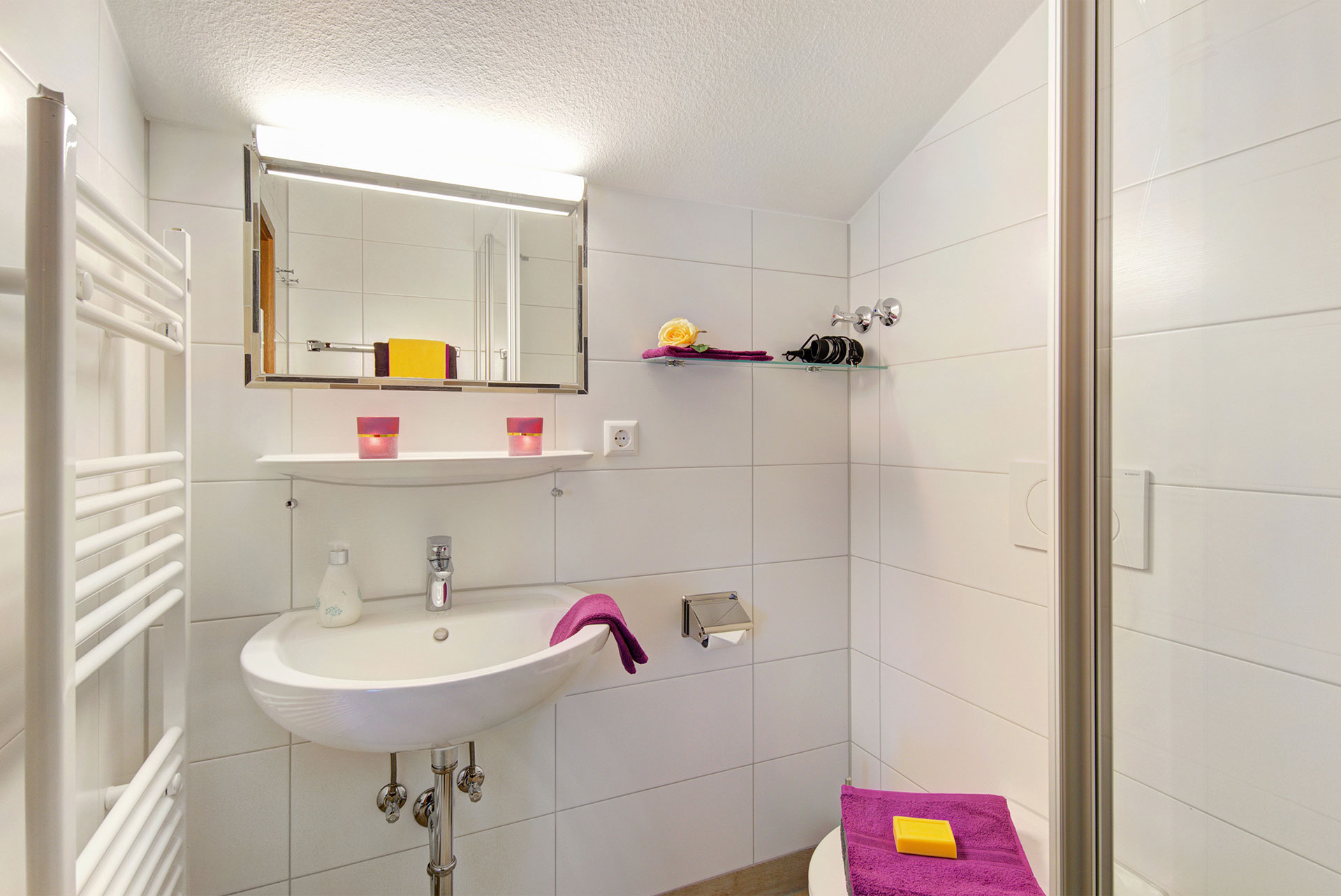 badezimmer mit waschbecken lila handtücher und teelichter in ferienwohnung