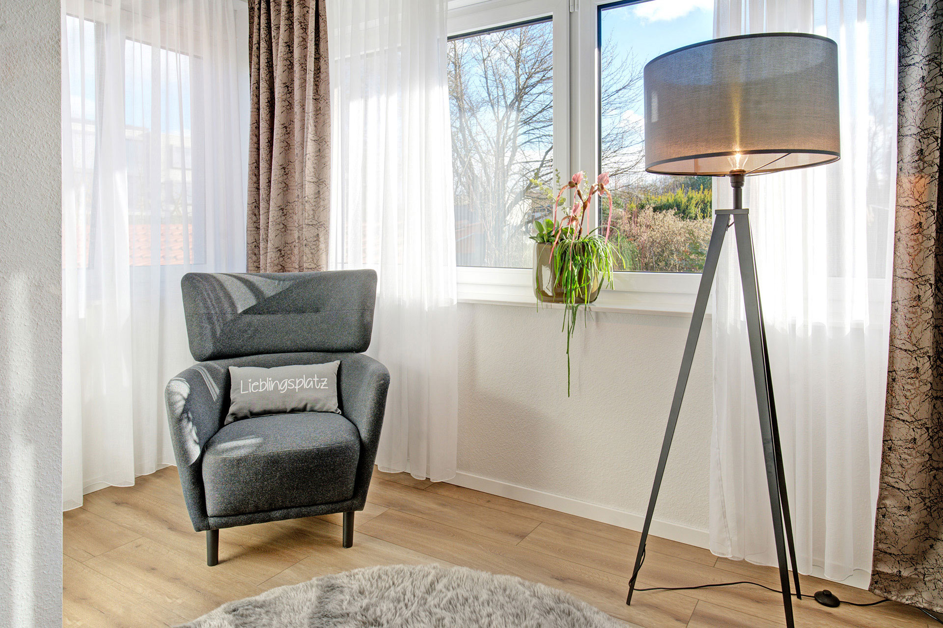 sessel mit lieblingsplatzkissen und stehlampe in ferienwohnung