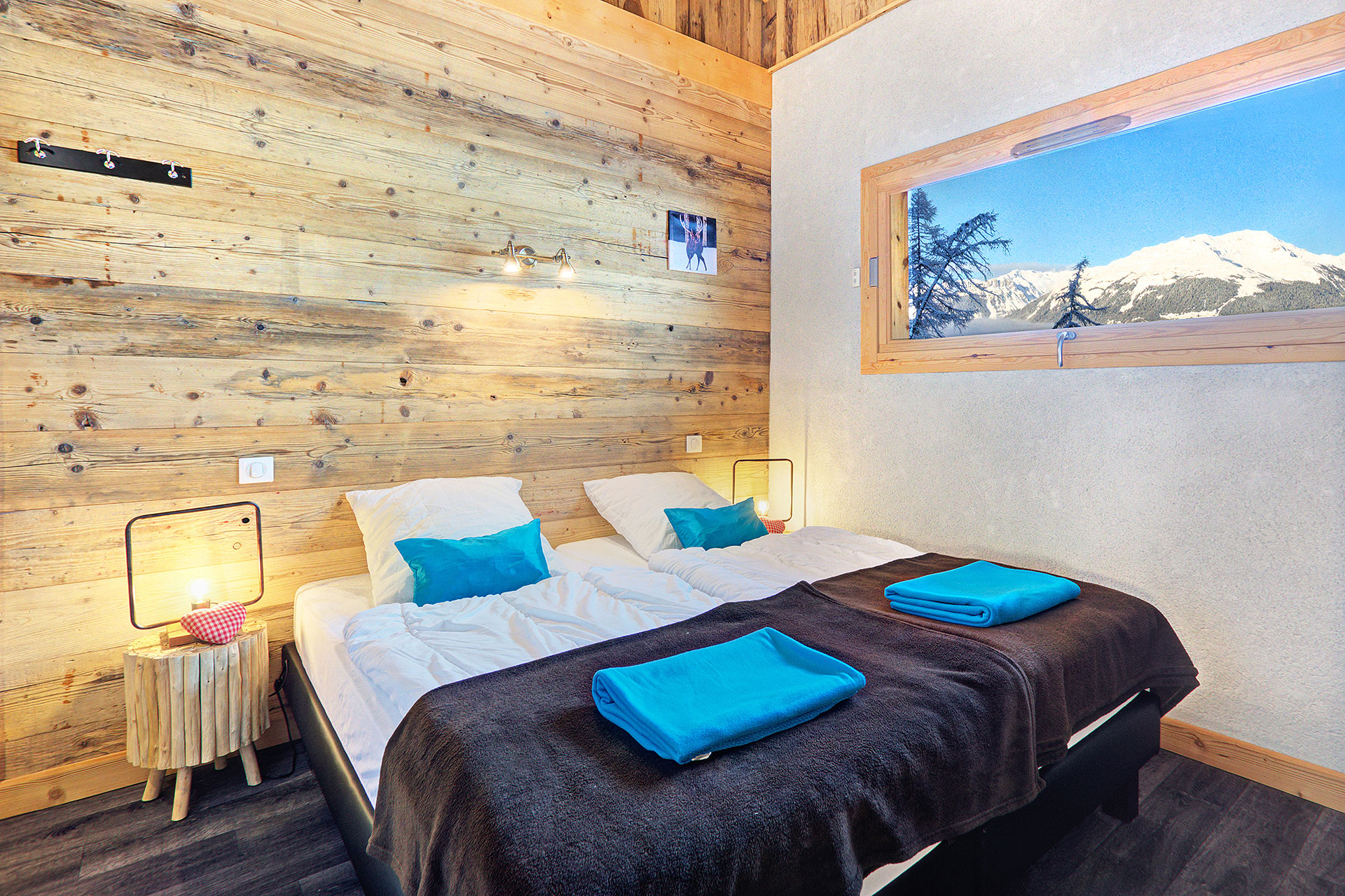 ferienhaus foto doppelzimmer mit tuerkisfarbenen decken und kissen und blick auf fenster mit schneebergpanorama