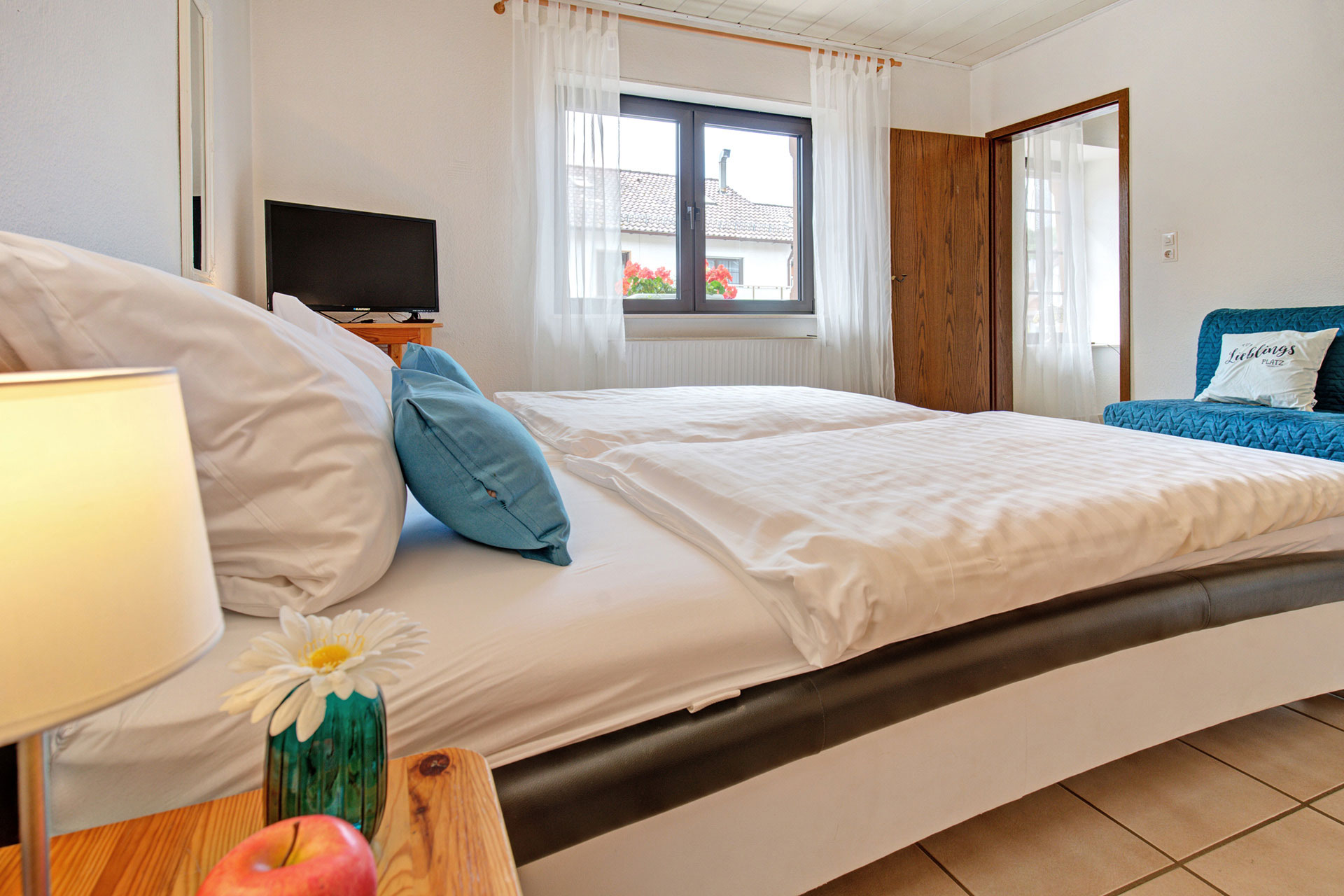 Doppelzimmer mit Blick vom Nachttisch zum Fenster