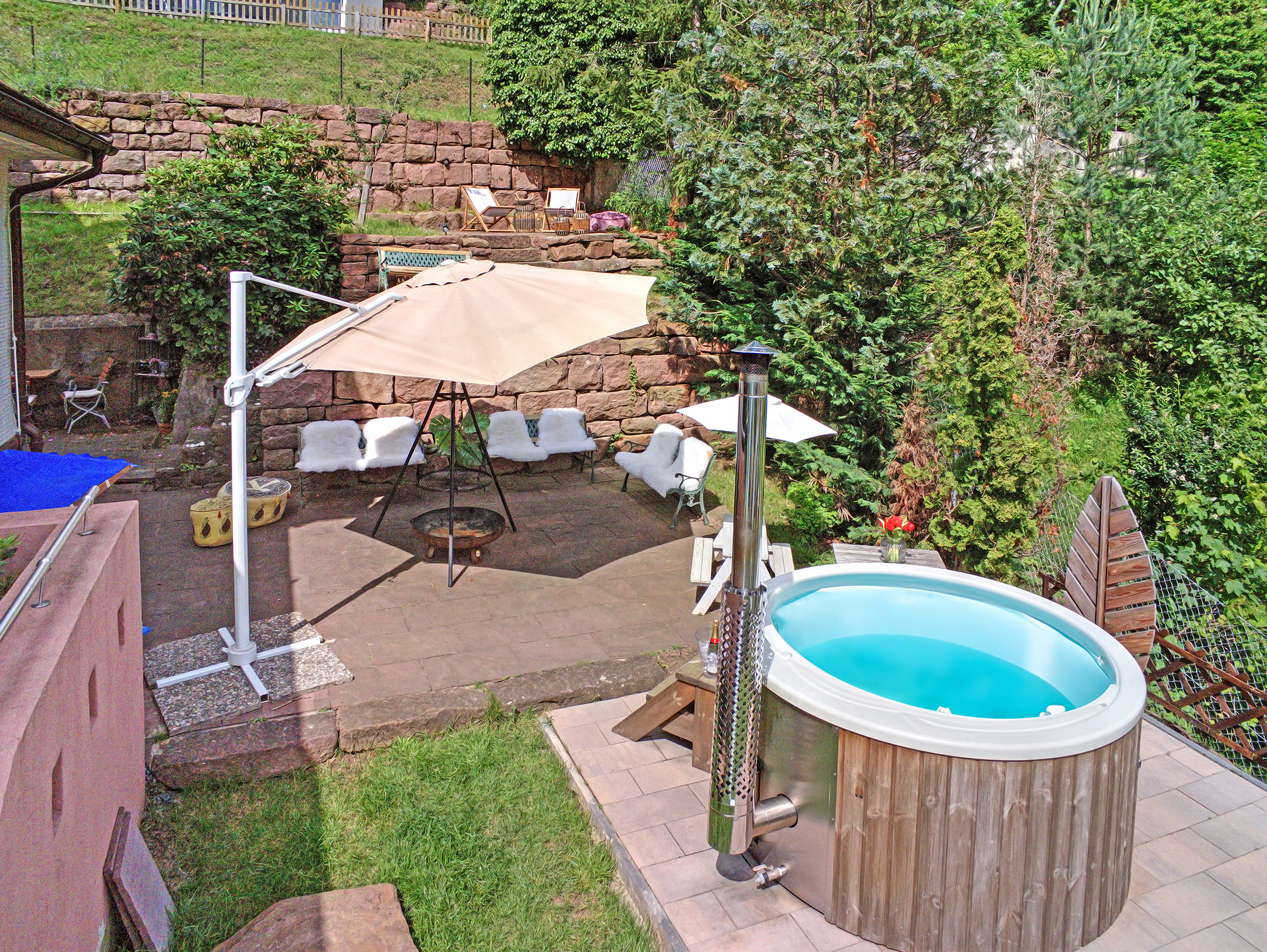 Garten des Schwarzwaldhaus mit gefülltem Outdoor-Whirlpool und gemütlicher Feuerstelle, fotografiert aus der Luft - foto optimiert
