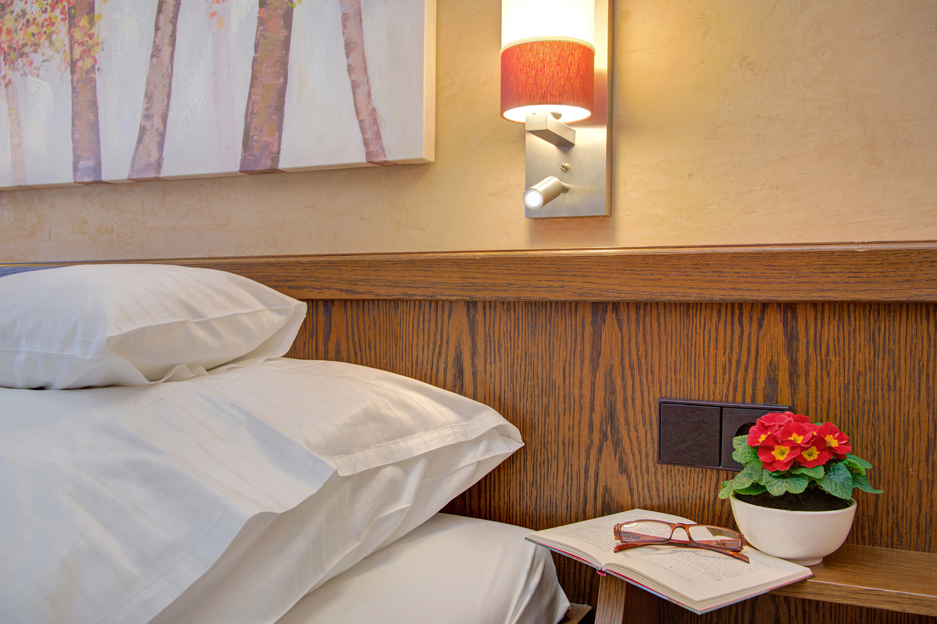 hotelfoto Einzelzimmer nachttisch mit buch brille blumen