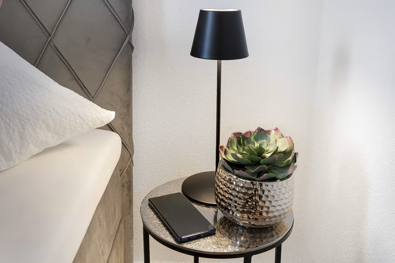 Nachttisch mid led lampe smartphone und kleiner pflanze