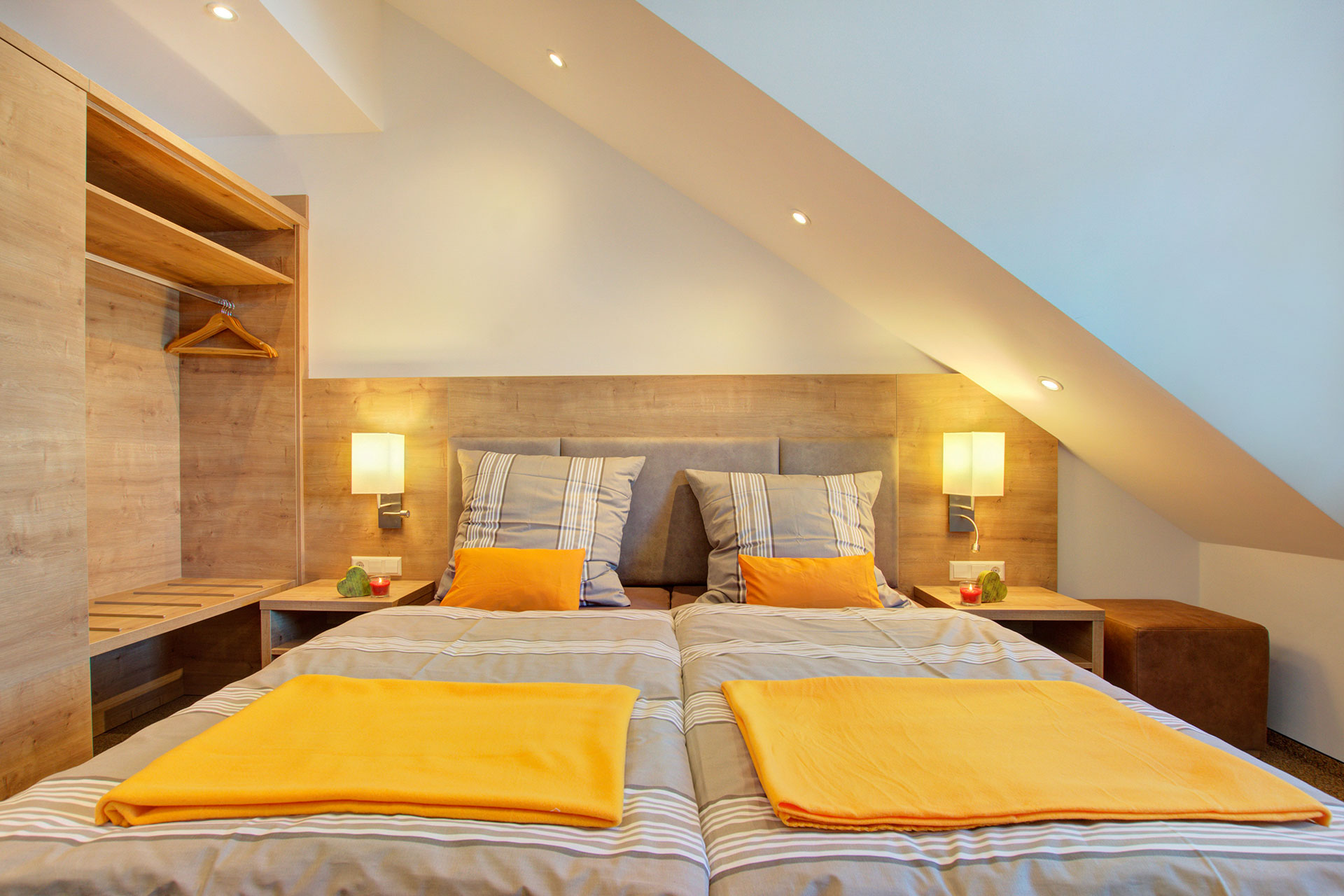 foto ferienwohnung doppelbett frontal mit orangenen decken sowie kissen 