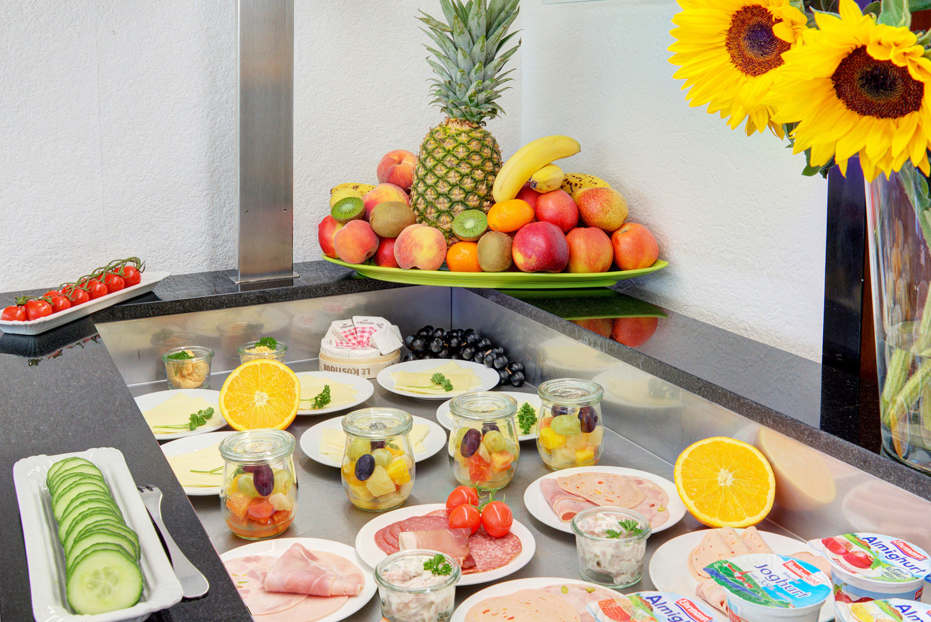 frühstücksbuffet mit grosser obstplatte seitlich sonnenblumen in hotel