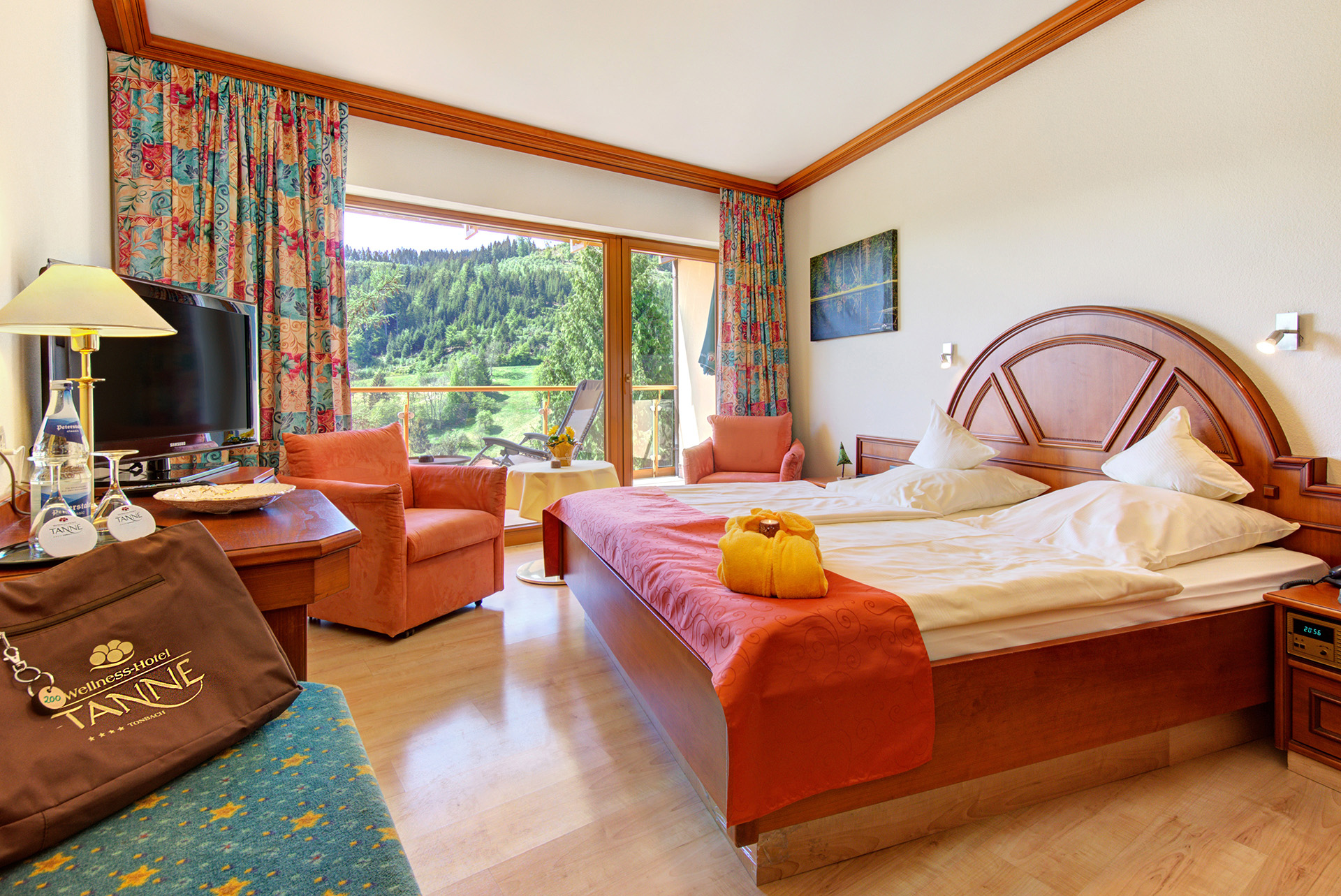 hotelfotograf doppelzimmer mit rotem bettläufer und sessel und mit gartenblick