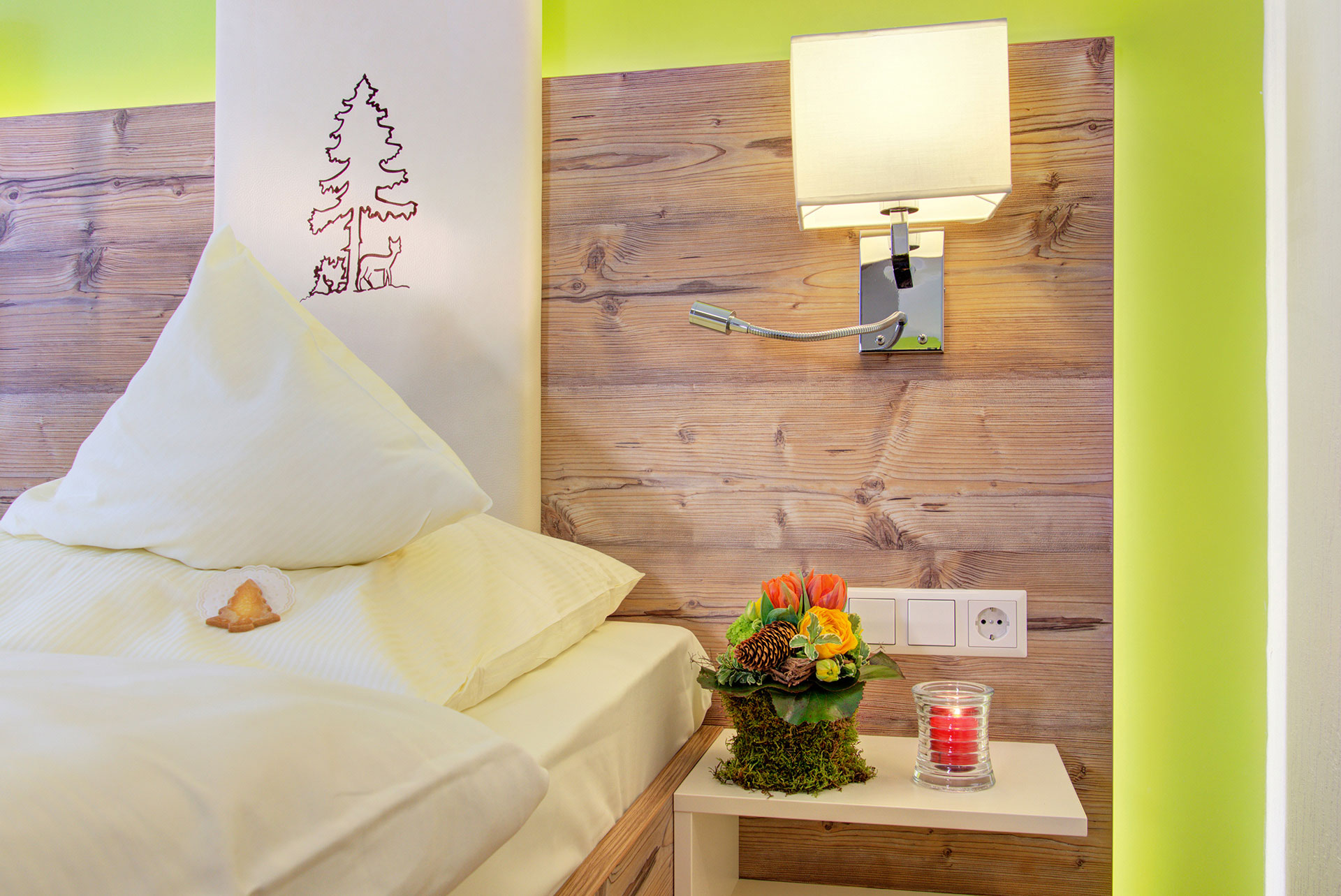nachttisch im doppelzimmer mit blumenbouquet und teelicht in hotel