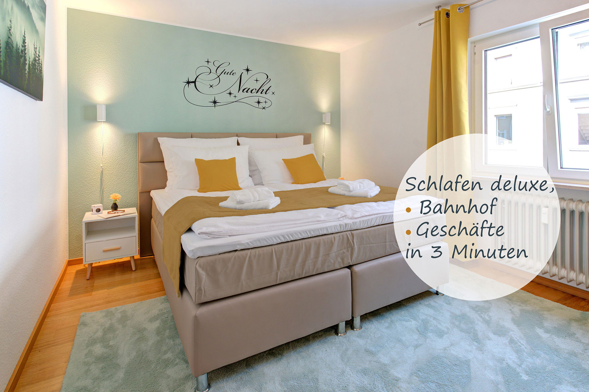 Modernes Schlafzimmer in einer Ferienwohnung; optisch bearbeiteter Button auf dem Bild mit der Aufschrift "schlafen deluxe" und Hinweis "Geschäfte nur 3 Minuten entfernt"