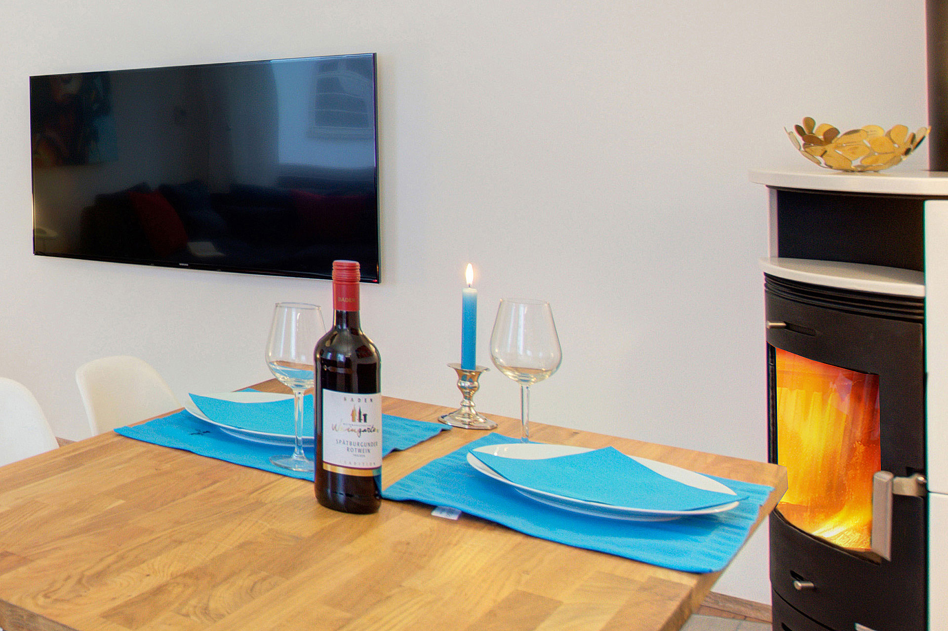 fotografin dekoriert zwei türkisfarbene gedecke mit weinflasche und tv-monitor