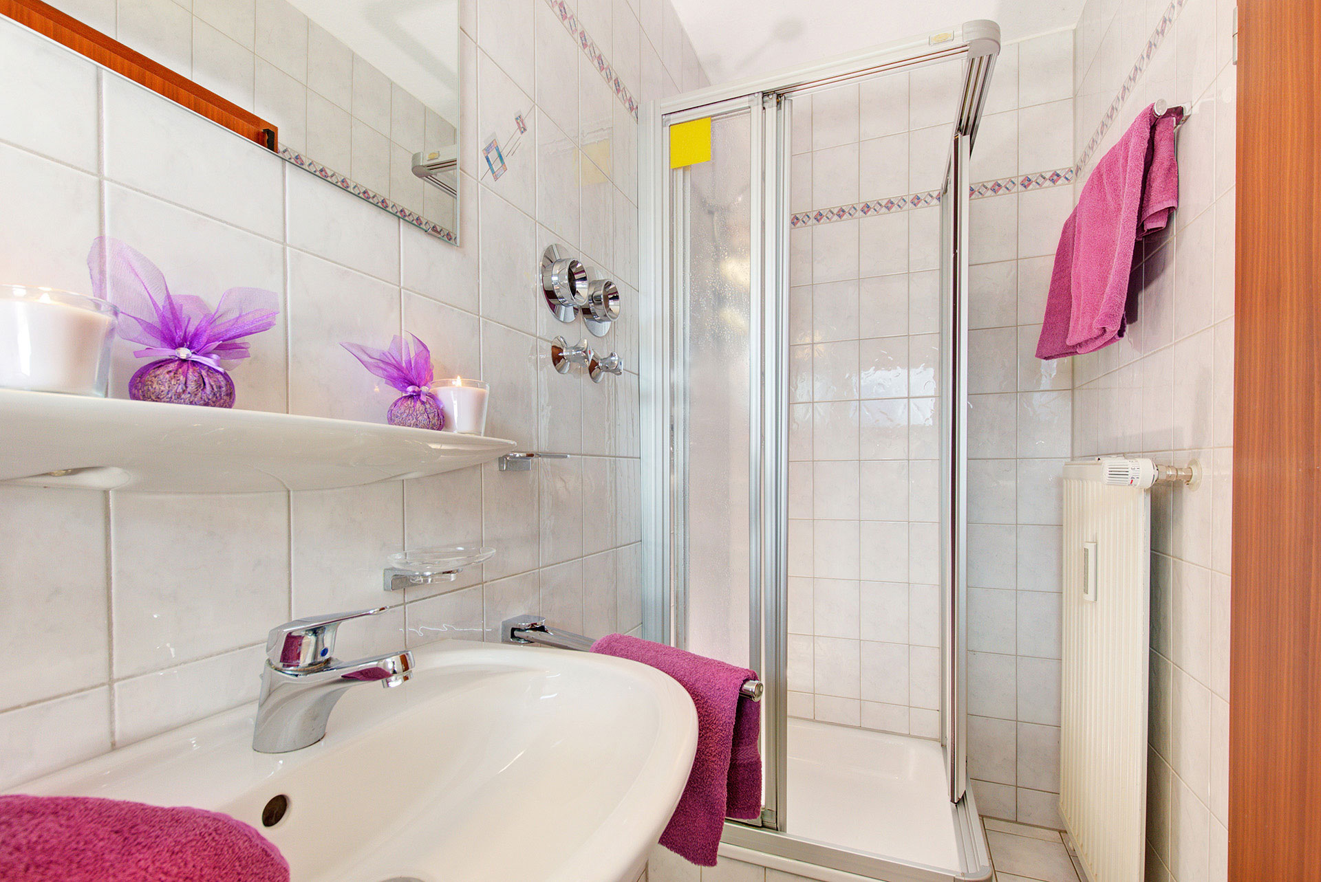 foto ferienwohnung waschecken und dusche mit lila handtücher