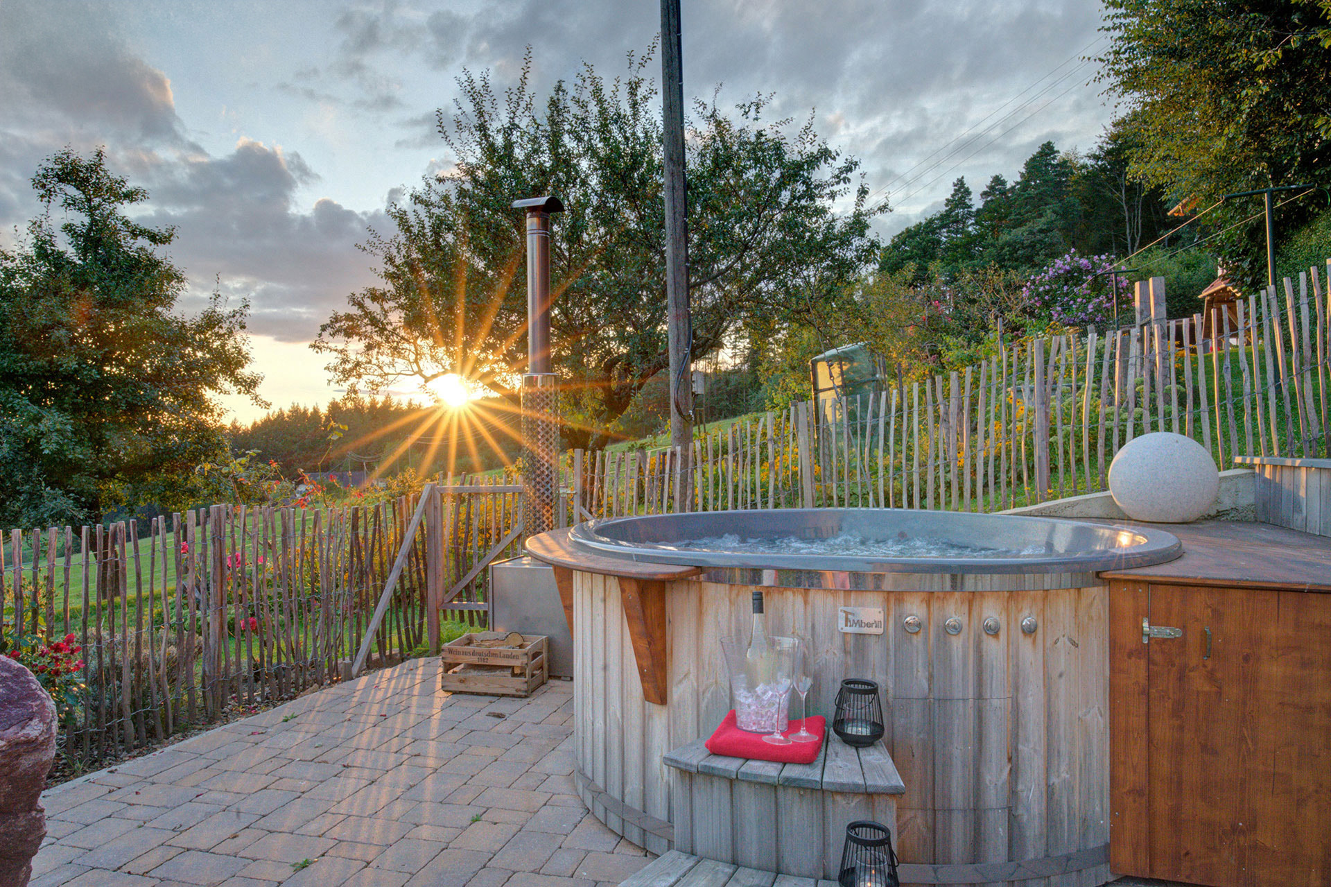 hot tub vor einem sonnenuntergang mit sektgedeck und teelichtern