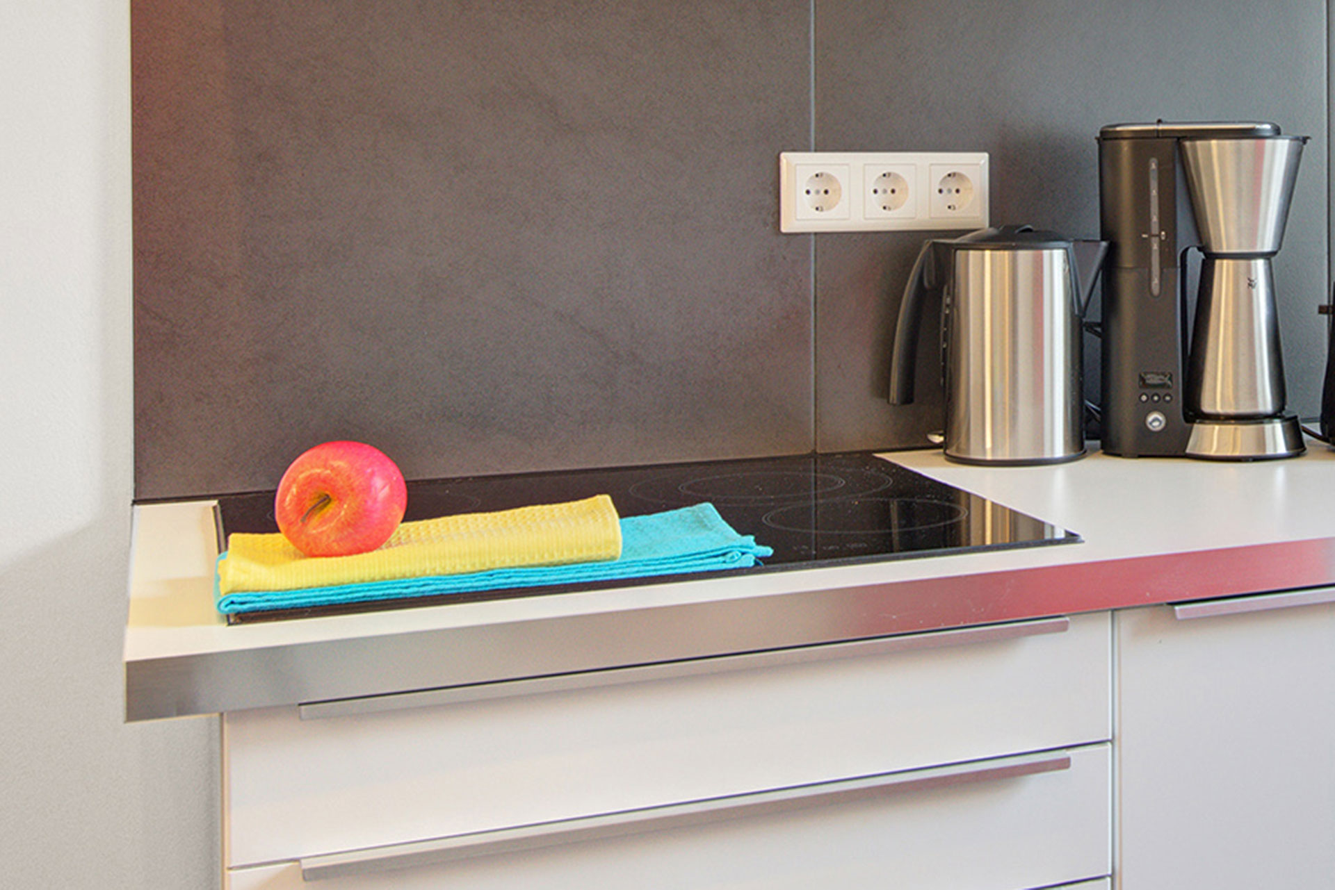 fotografin dekoriert ceranherd mit türkisem und gelbem geschirrhandtuch mit rotem apfel