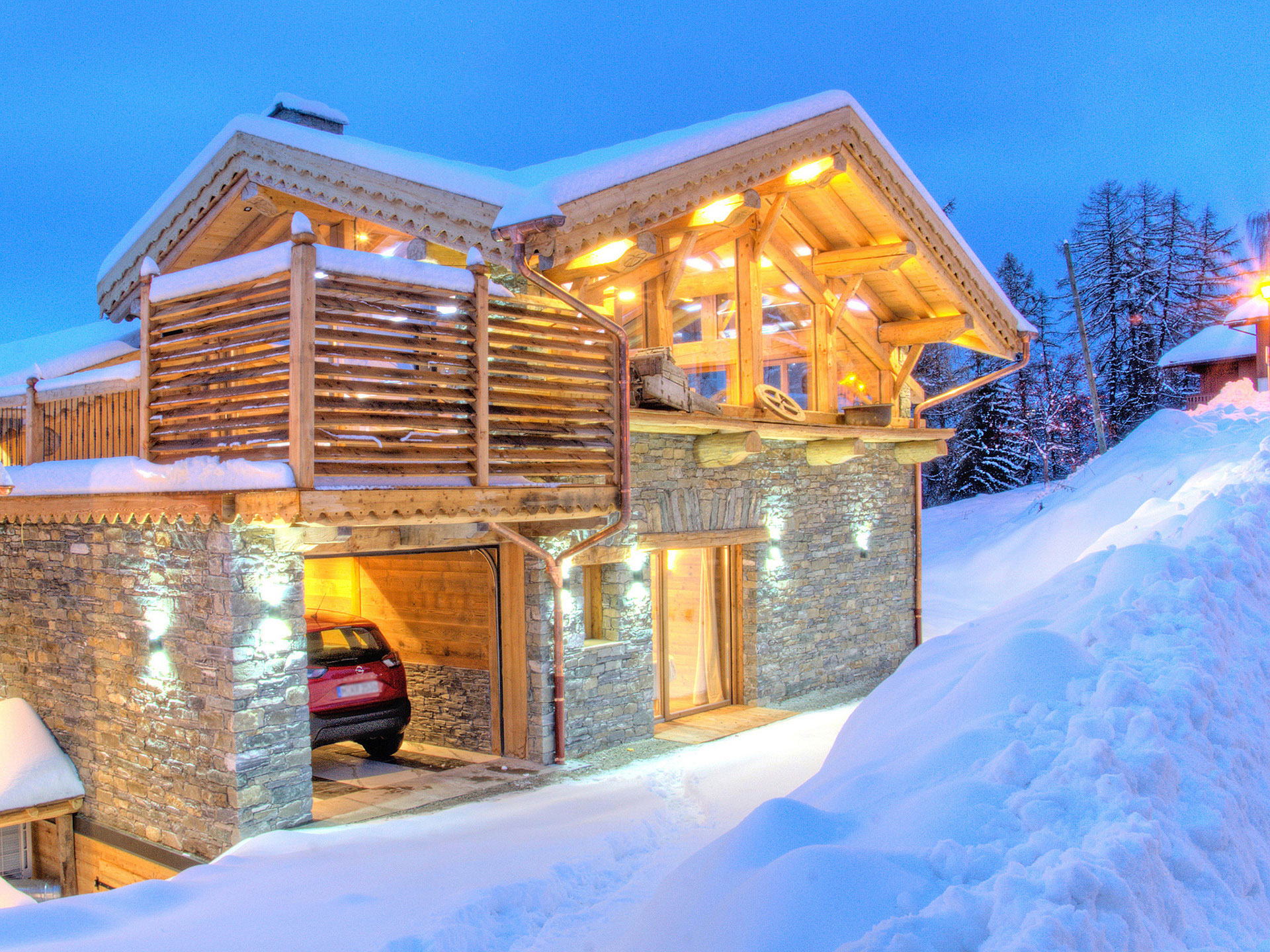 Hochwertiges Immobilienfoto - Aussenansicht bei Abendstimmung vom beleuchteten Chalet im Schnee