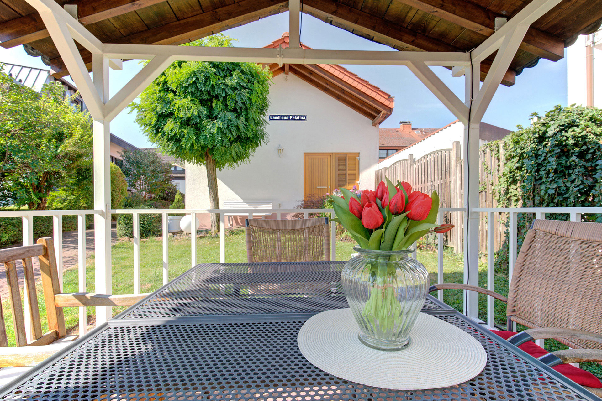 laubendruchblick mit rotem tulpenstrauss auf baum mit anbau ferienwohnung  - fotograf für ferienwohnungen