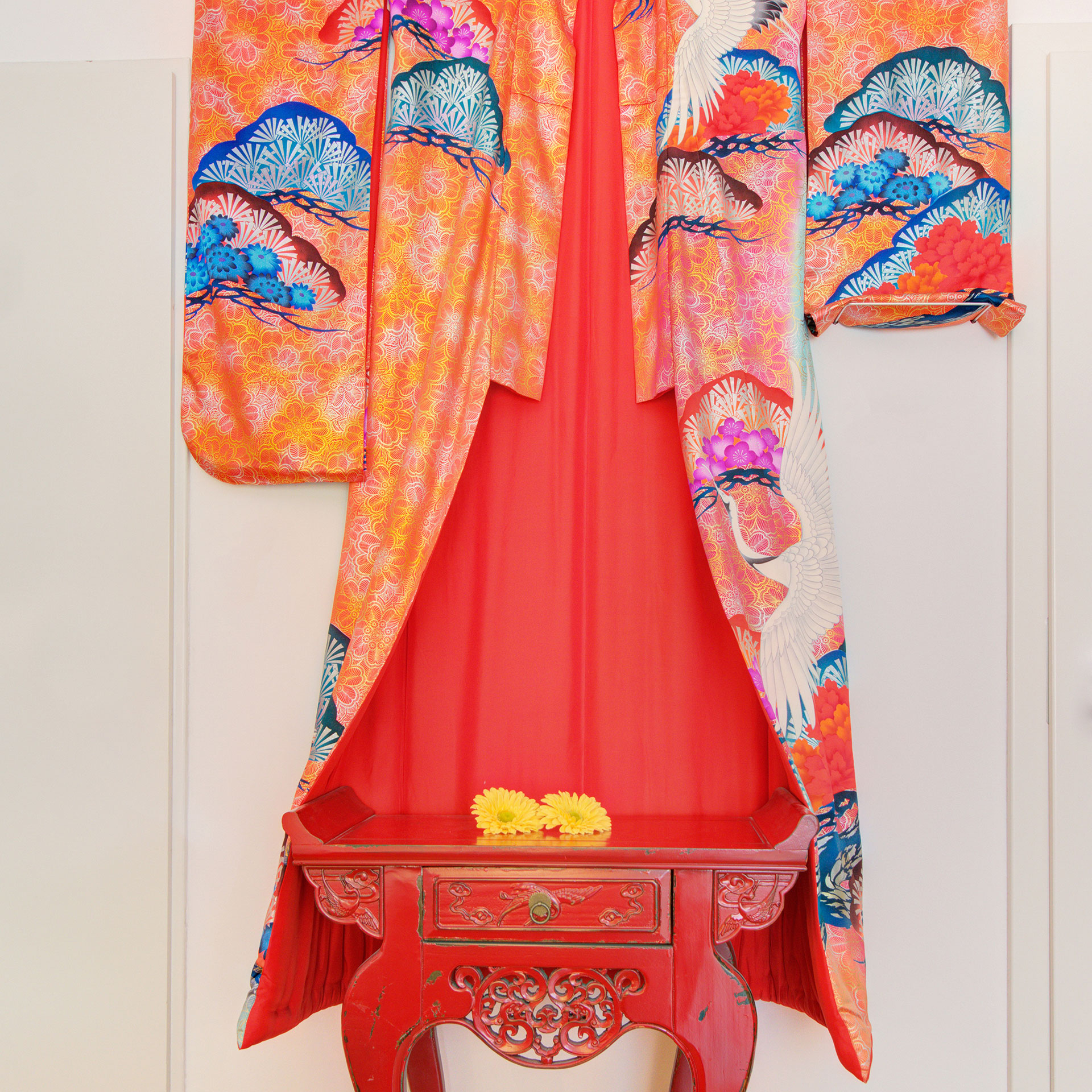 hotelfotograf asiatisches roter kimono mit kleiner Kommode und gelber gerbara