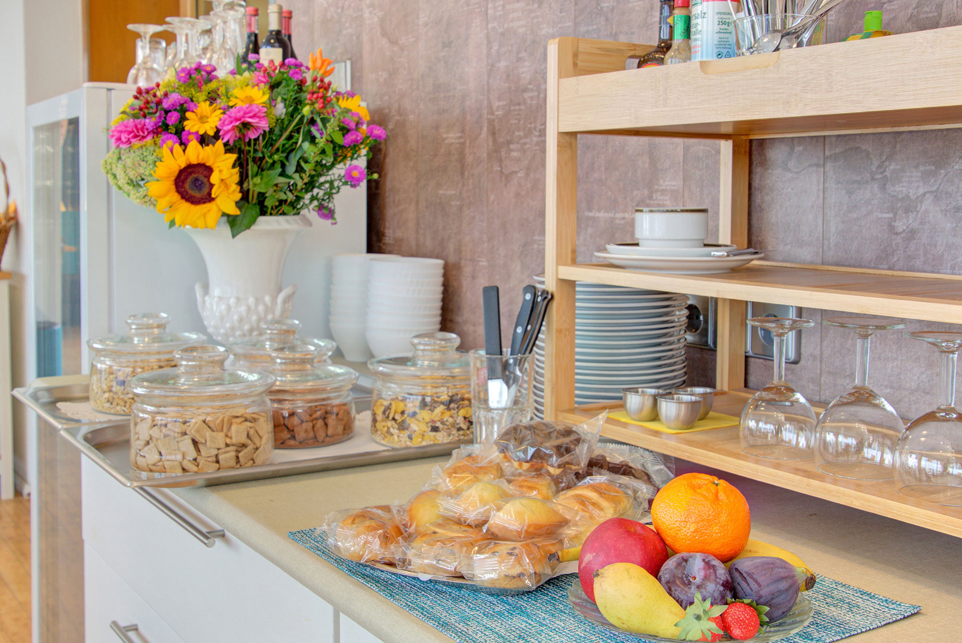 hotelfotograf buffet mit abgepackten kuchenstueckchen und kleiner obstplatte sowie sonnenblumenstrauss